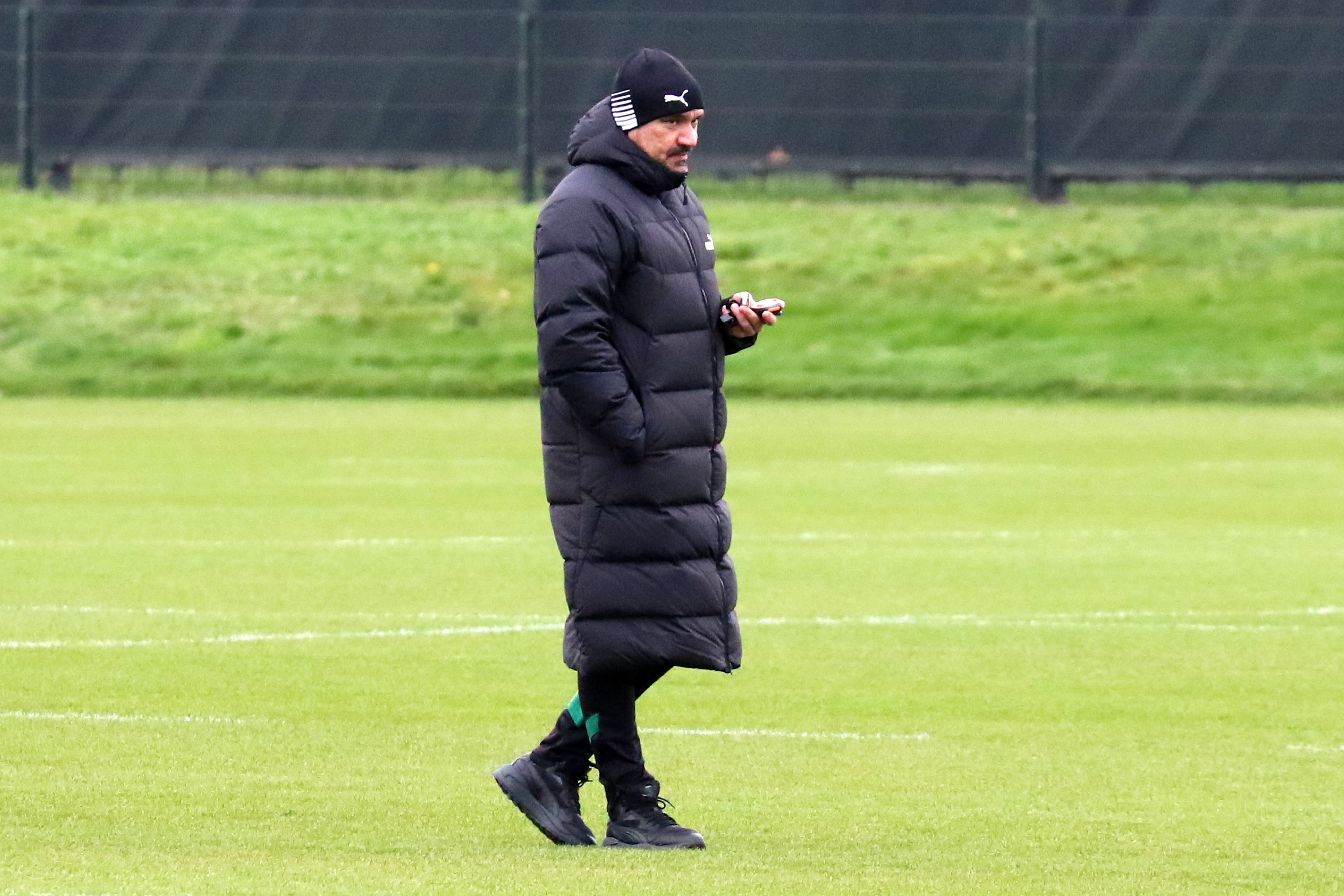 Trainer Daniel Farke beobachtet das Training von Borussia Mönchengladbach am 31. Dezember 2022. Farke trägt eine Mütze und eine knielange Jacke, in der linken Hand hält er eine Stoppuhr