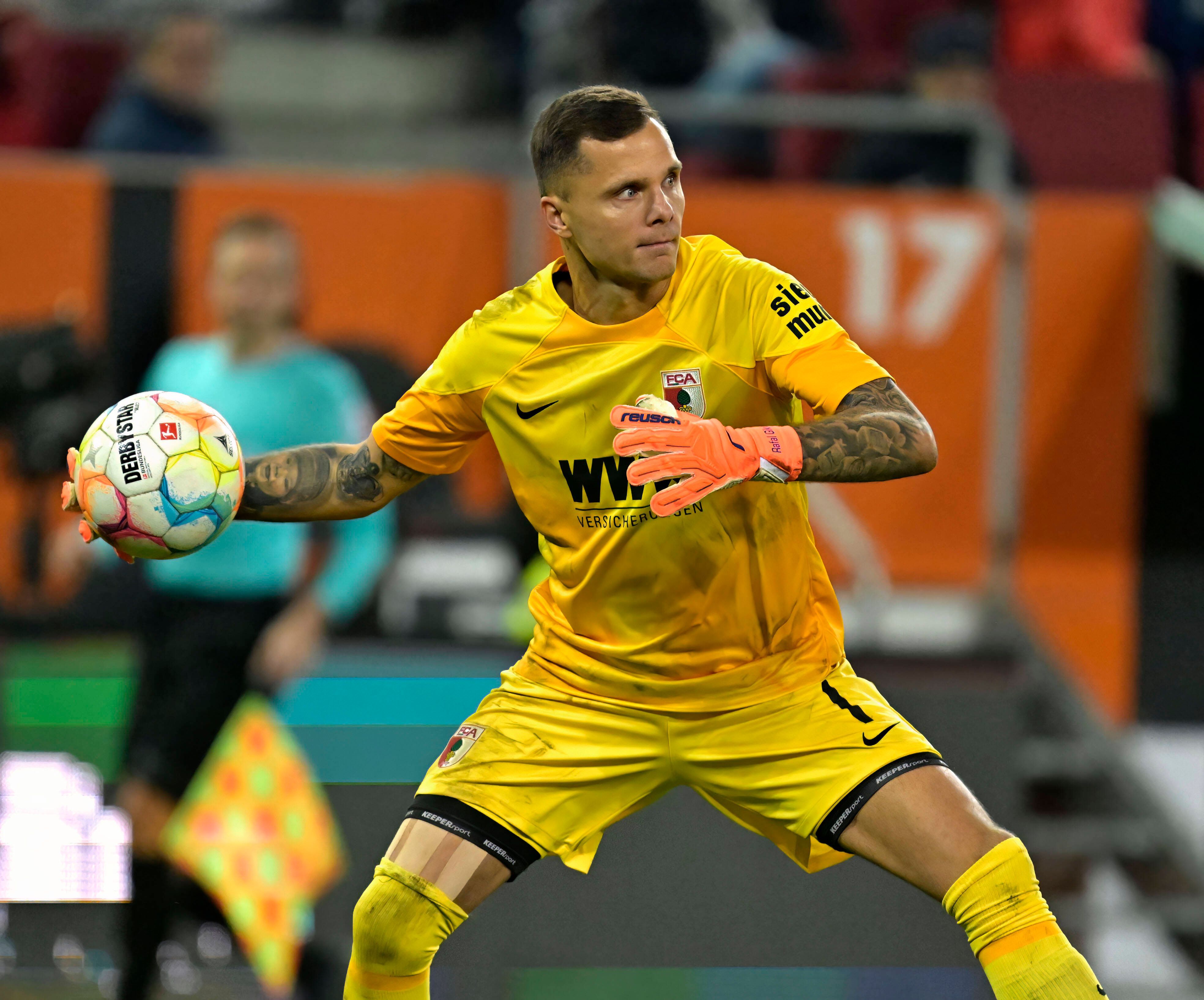 Torwart Rafal Gikiewicz vom FC Augsburg, hier beim Bundesliga-Spiel gegen den VfL Bochum am 12. November 2022, macht im gelben Trikot einen Abwurf.