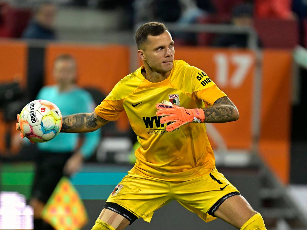 Torwart Rafal Gikiewicz vom FC Augsburg, hier beim Bundesliga-Spiel gegen den VfL Bochum am 12. November 2022, macht im gelben Trikot einen Abwurf.
