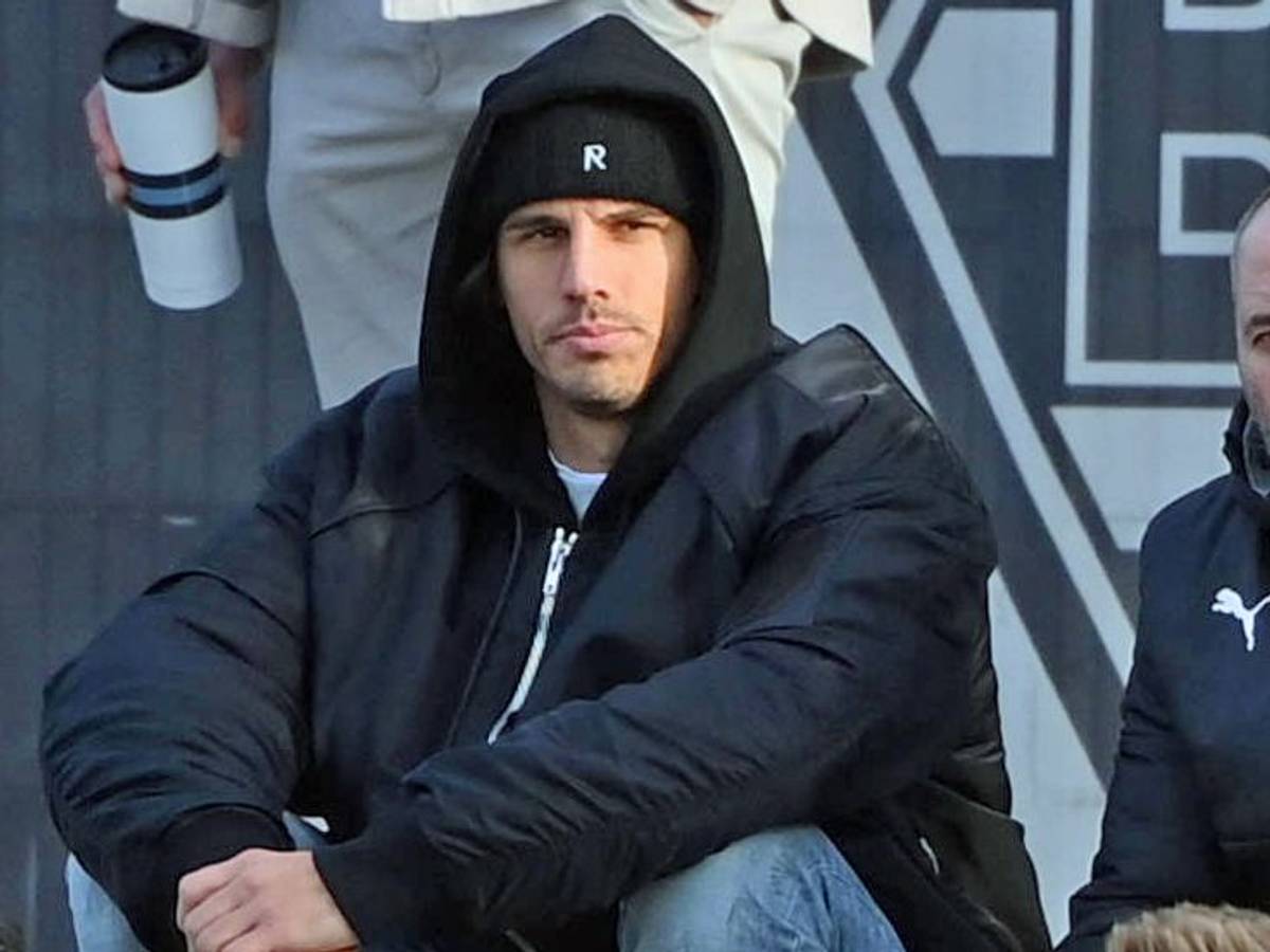 Gladbach-Torwart Yann Sommer (l.) sitzt am Samstag (7. Januar 2023) neben Co-Trainer Oliver Neuville (r.) und beobachtet das Testspiel seiner Team-Kollegen gegen Drittligist Oldenburg. Sommer hat eine Mütze auf.