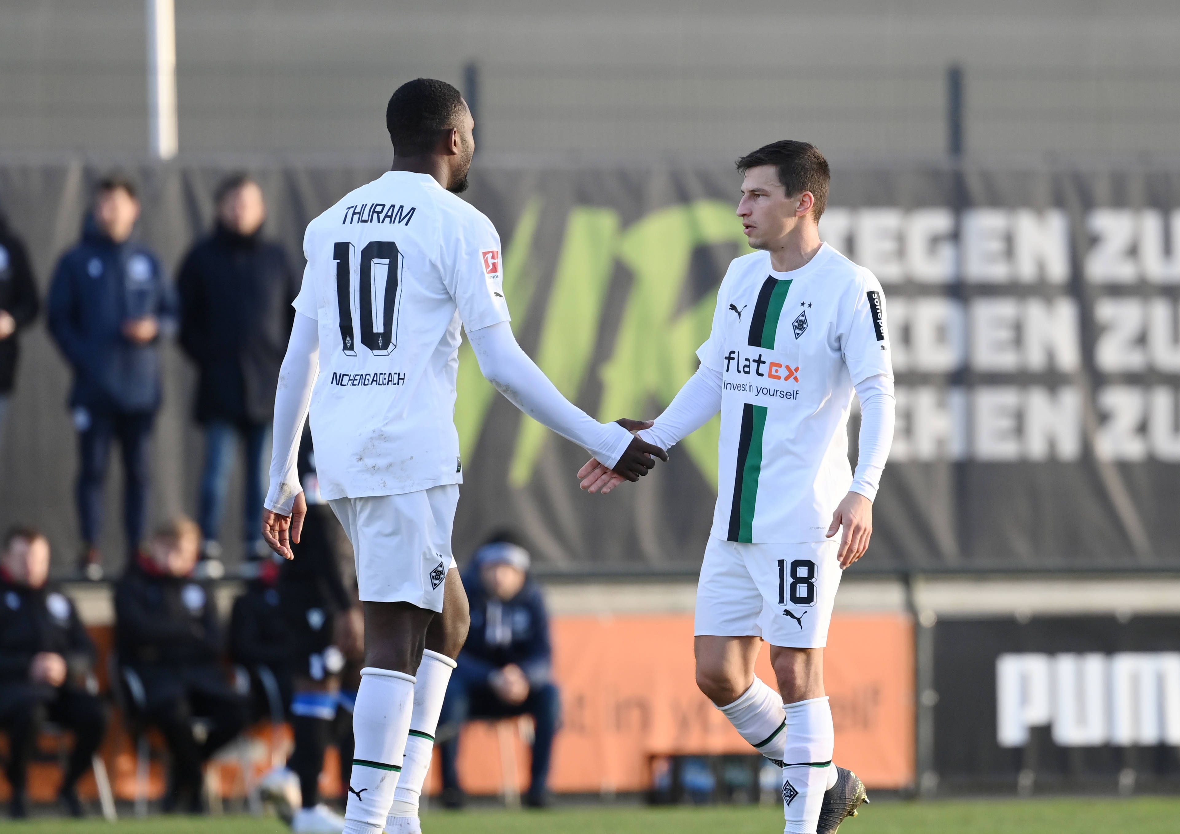 Marcus Thuram (l.) und Stefan Lainer (r.) von Borussia Mönchengladbach beim Testspiel gegen Arminia Bielefeld am 11. Januar 2023 klatschen beim Wechsel ab. Thuram ist dabei von hinten zu sehen, Lainer in einer seitlichen Frontansicht.
