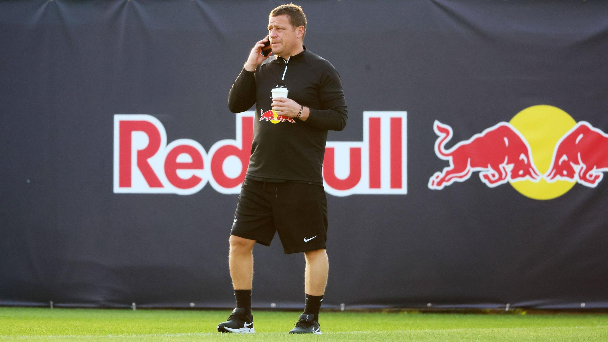 Ex-Gladbach-Manager Max Eberl, hier am 9. Januar 2023 im Trainingscamp seines neuen Klubs RB Leipzig in Abu Dhabi zu sehen. Eberl telefoniert mit seinem Smartphone, in der linken Hand hält er einen Getränkebecher.