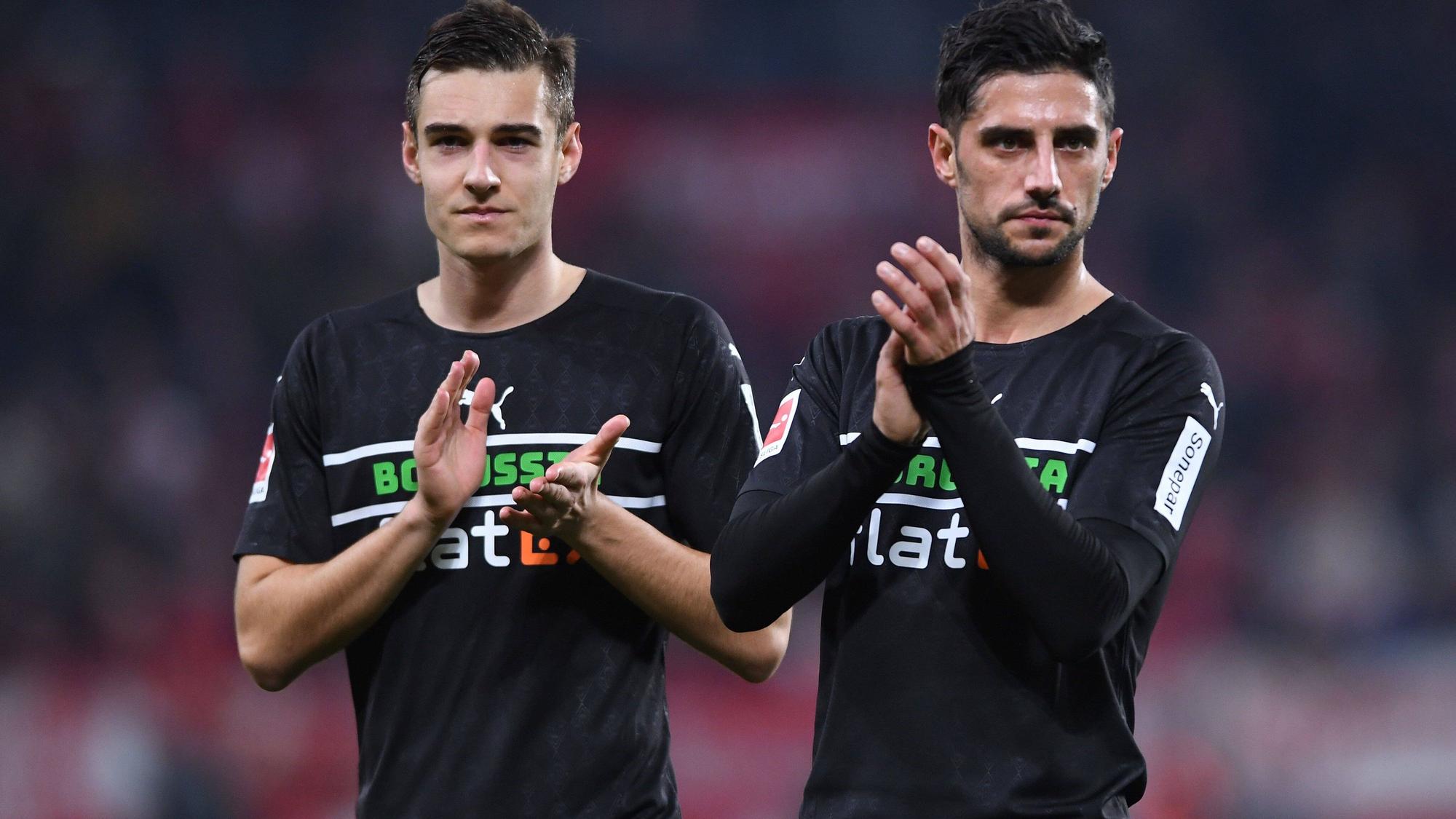 Florian Neuhaus (l.) und Lars Stindl (r.) von Borussia Mönchengladbach, hier am 5. November 2021 beim Auswärtsspiel in Mainz, klatschen nach der Partie den mitgereisten Fans zu. Beuide schauen missmutig und haben ein schwarzes Gladbach-Trikot an.