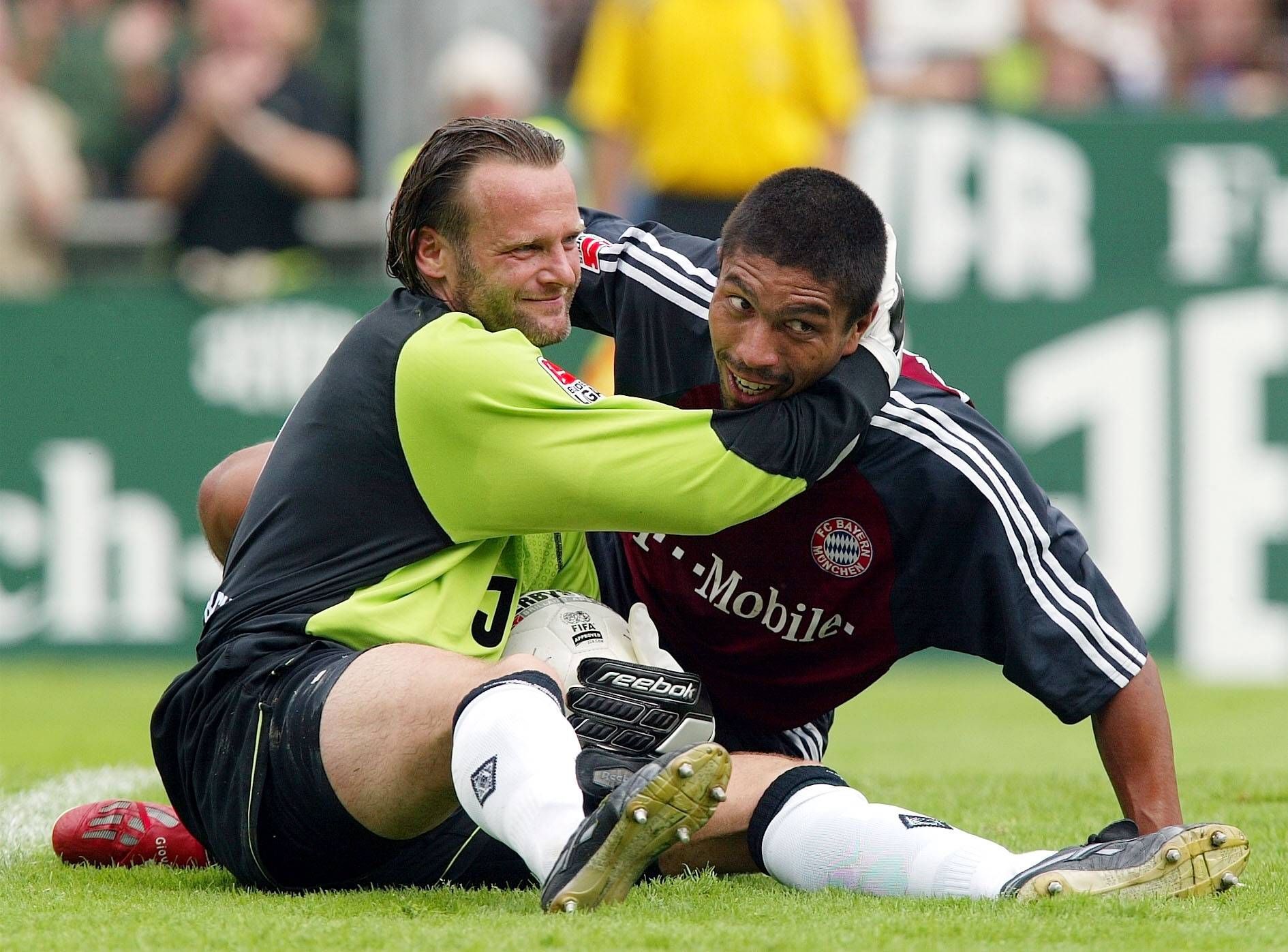 Jörg Stiel (l.) umarmt Giovane Elber nach einer Parade im Spiel von Borussia Mönchengladbach gegen den FC Bayern München am 1. Spieltag der Saison 2002/2003. Beide Spieler liegen noch am Boden, berühren aber den Kopf des anderen als Fair-Play-Geste.