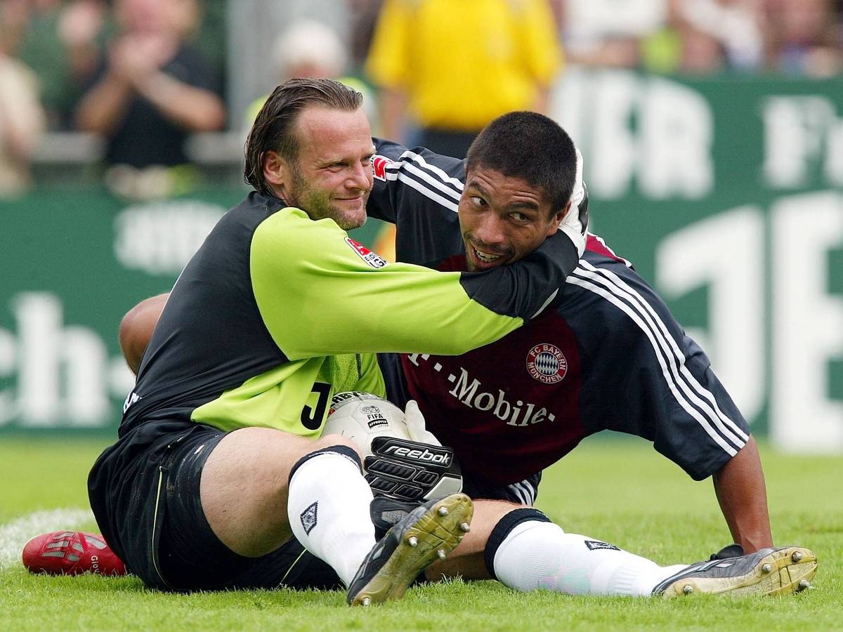 Jörg Stiel (l.) umarmt Giovane Elber nach einer Parade im Spiel von Borussia Mönchengladbach gegen den FC Bayern München am 1. Spieltag der Saison 2002/2003. Beide Spieler liegen noch am Boden, berühren aber den Kopf des anderen als Fair-Play-Geste.
