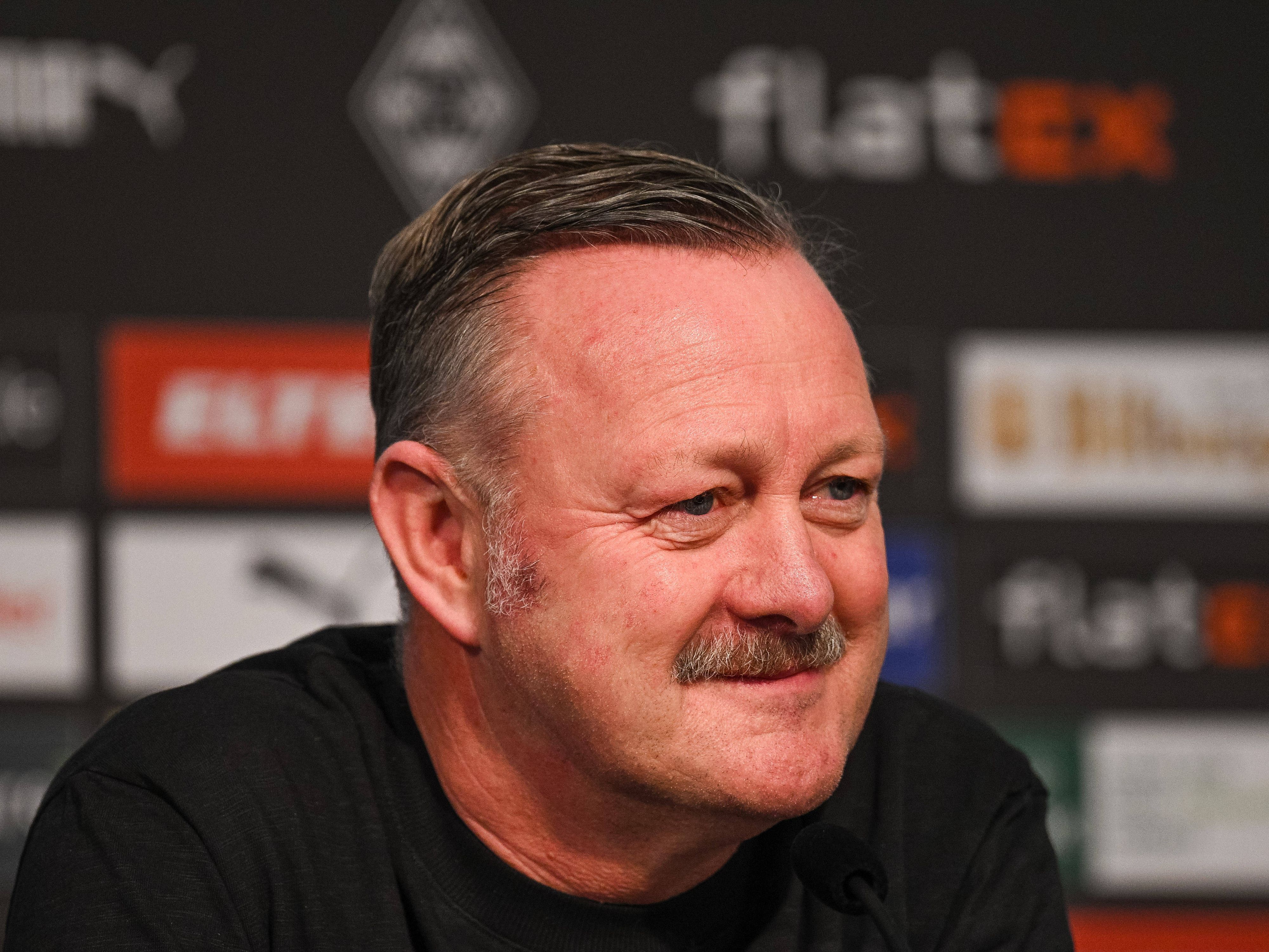 Roland Virkus ist Sportdirektor bei Fußball-Bundesligist Borussia Mönchengladbach. Auf diesem Foto ist er am 20. Januar 2023 während einer Pressekonferenz im Borussia-Park zu sehen. Virkus lächelt im Presseraum, er trägt einen dunken Pulli.