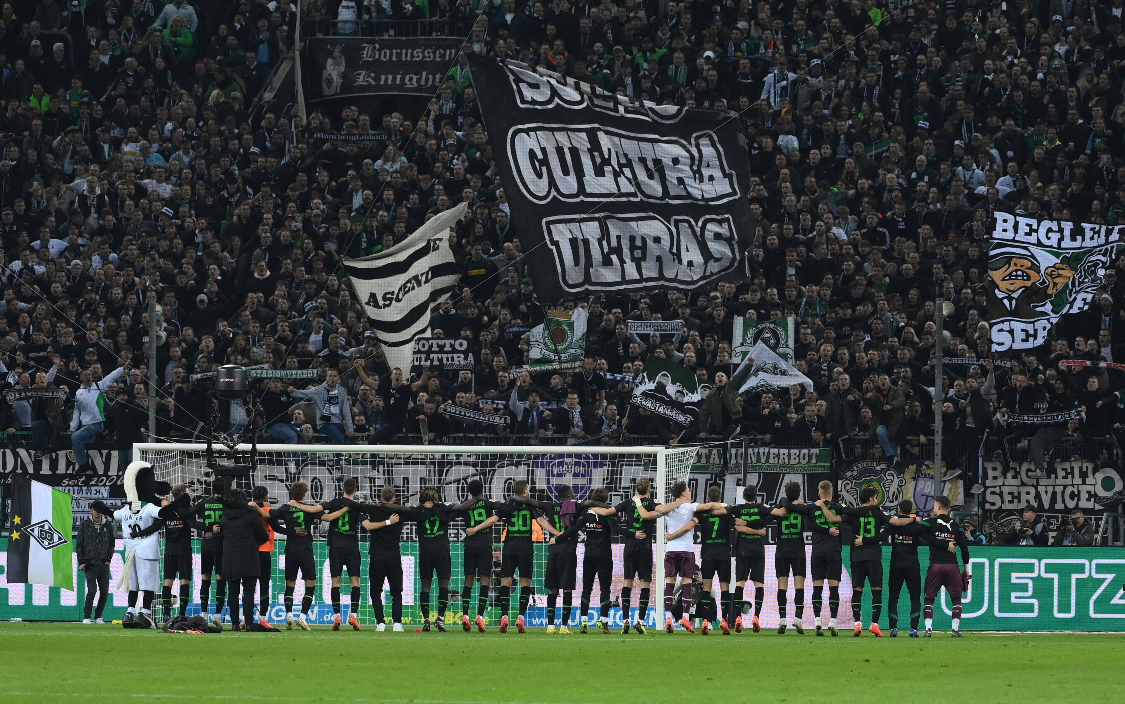 Die Spieler von Borussia Mönchengladbach stehen Arm in Arm vor der Nordkurve im Borussia-Park und feiern den Bundesliga-Sieg gegen Borussia Dortmund am 11. November 2022 mit den Fans auf der Stehplatz-Tribüne.