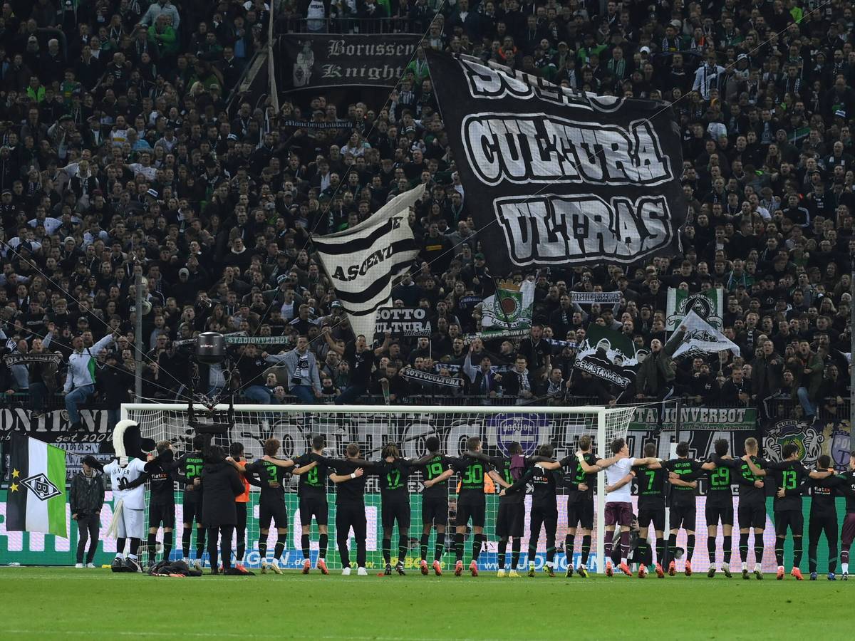 Die Spieler von Borussia Mönchengladbach stehen Arm in Arm vor der Nordkurve im Borussia-Park und feiern den Bundesliga-Sieg gegen Borussia Dortmund am 11. November 2022 mit den Fans auf der Stehplatz-Tribüne.