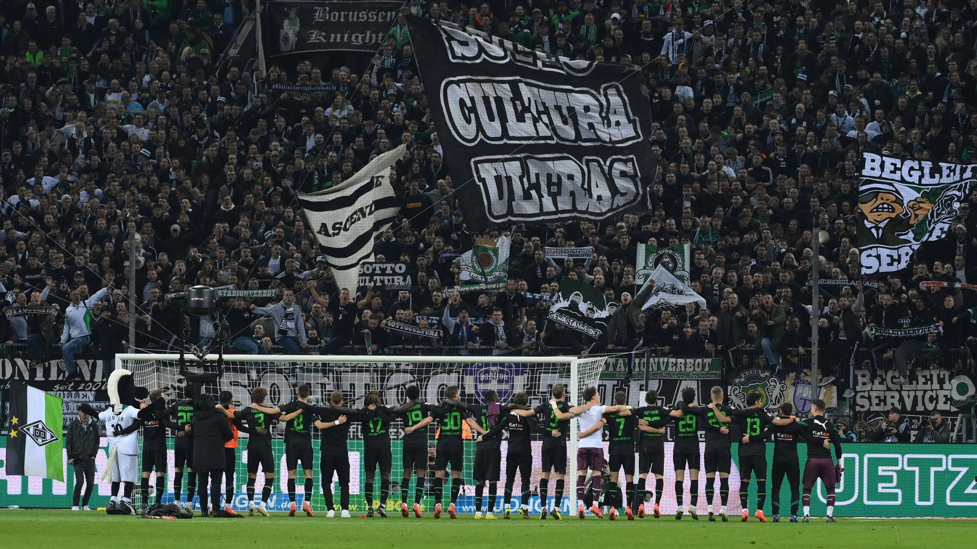 Die Spieler von Borussia Mönchengladbach stehen Arm in Arm vor der Nordkurve im Borussia-Park und feiern den Bundesliga-Sieg gegen Borussia Dortmund am 11. November 2022 mit den Fans auf der Stehplatz-Tribüne.