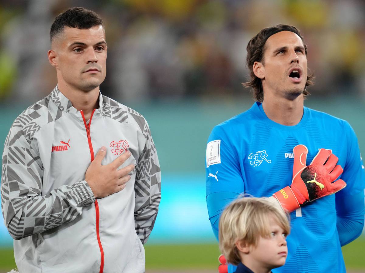 Granit Xhaka (l.) und Yann Sommer stehen vor dem WM-Spiel gegen Brasilien am 28. November 2022 nebeneinander bei der Nationalhymne. Beide Spieler der Schweiz legen ihre rechte Hand auf ihre Brust.