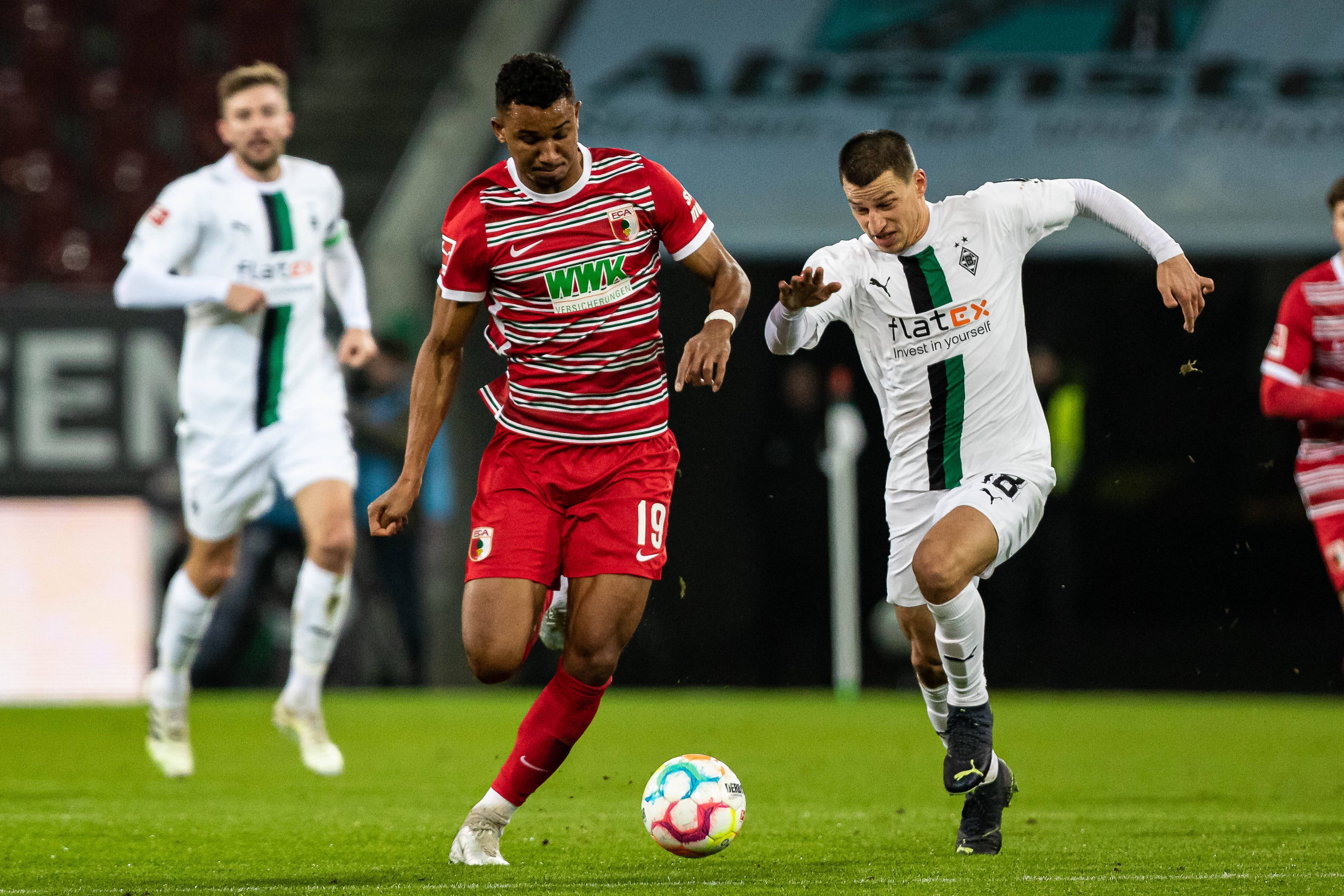 Gladbach-Verteidiger Stefan Lainer (r.) im Duell mit Felix Uduokhai (l.) vom FC Augsburg während des Bundesliga-Duells am Mittwoch (25. Januar 2023) in der WWK-Arena. Beide Spieler haben den Ball im Blick und sprinten.