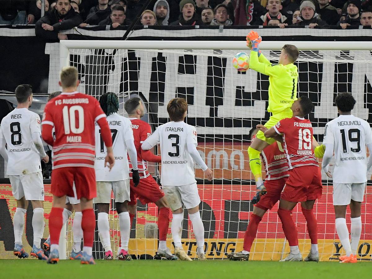 Jonas Omlin, Torwart von Borussia Mönchengladbach (in gelb), lässt den Ball fallen, Dion Beljo (verdeckt) trifft zum vermeintlichen 1:0 für den FC Augsburg. Das Tor am 25. Januar 2023 zählt aber aufgrund einer Abseitsstellung nicht.