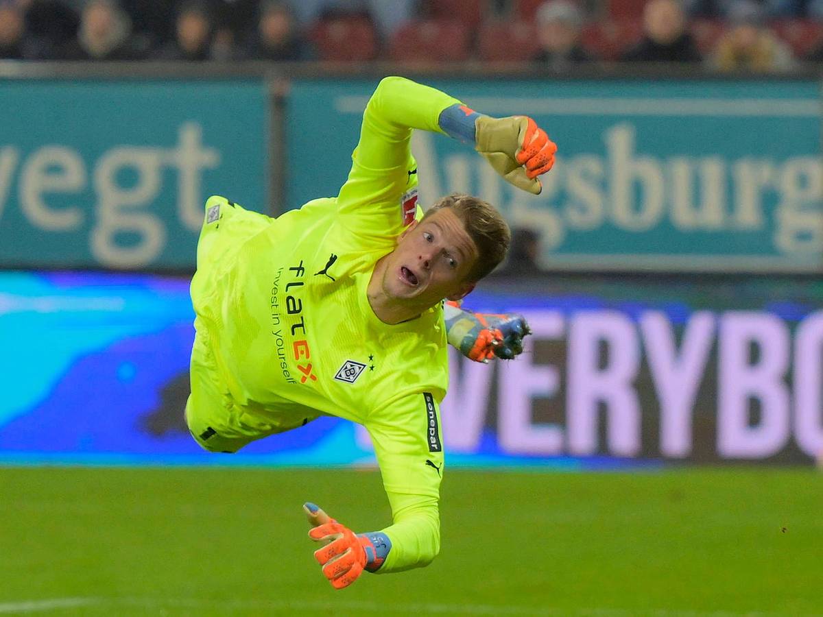 Jonas Omlin springt bei einer Parade im Bundesliga-Spiel von Borussia Mönchengladbach beim FC Augsburg am 25. Januar 2023 zur linken Seite. Omlin trägt ein knallgelbes Borussia-Trikot.