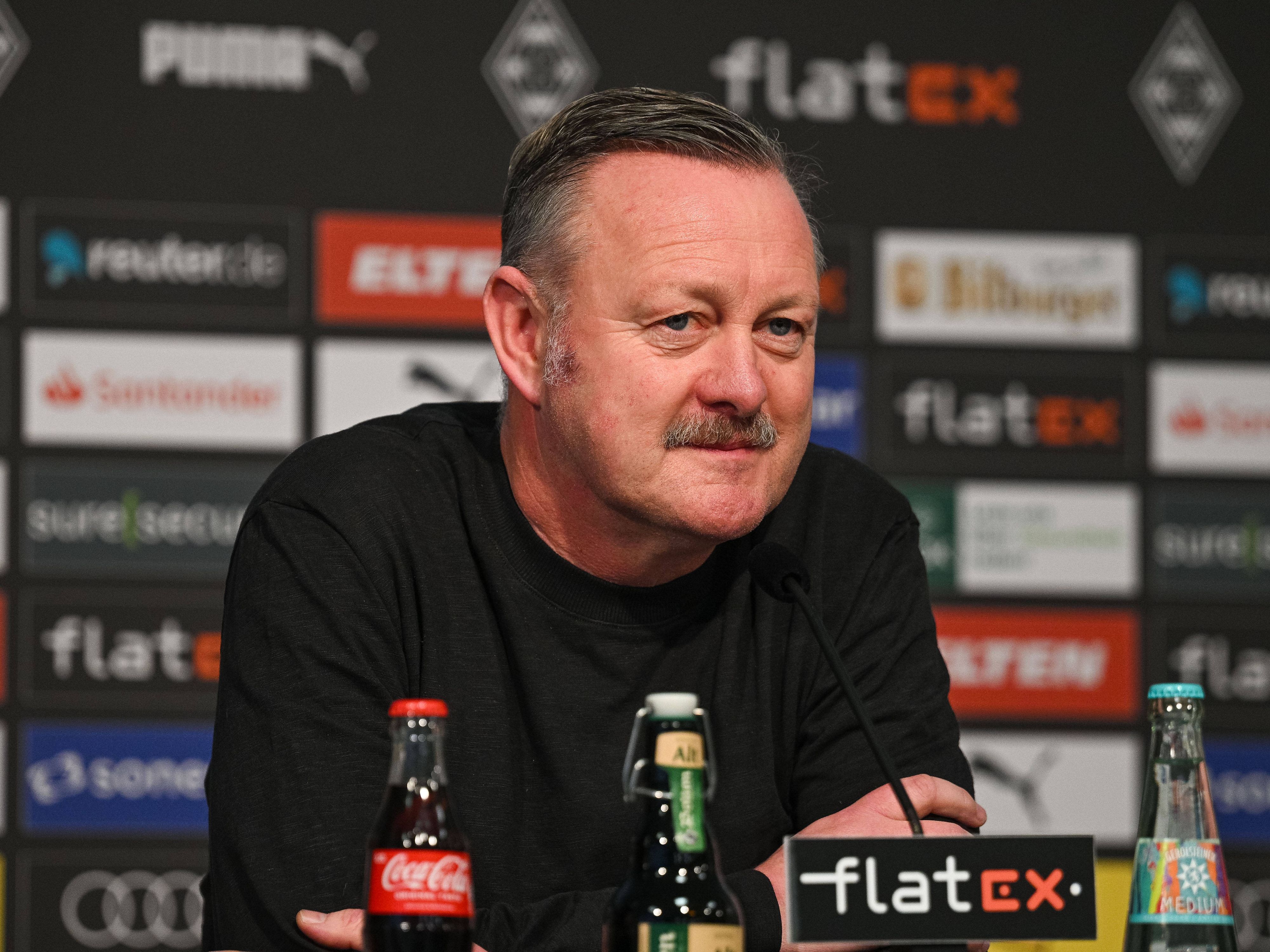 Roland Virkus, Manager von Borussia Mönchengladbach, bei einer Pressekonferenz am 20. Januar 2023 im Borussia-Park. Er schaut verschmitzt und ernst und trägt einen schwarzen Pullover.