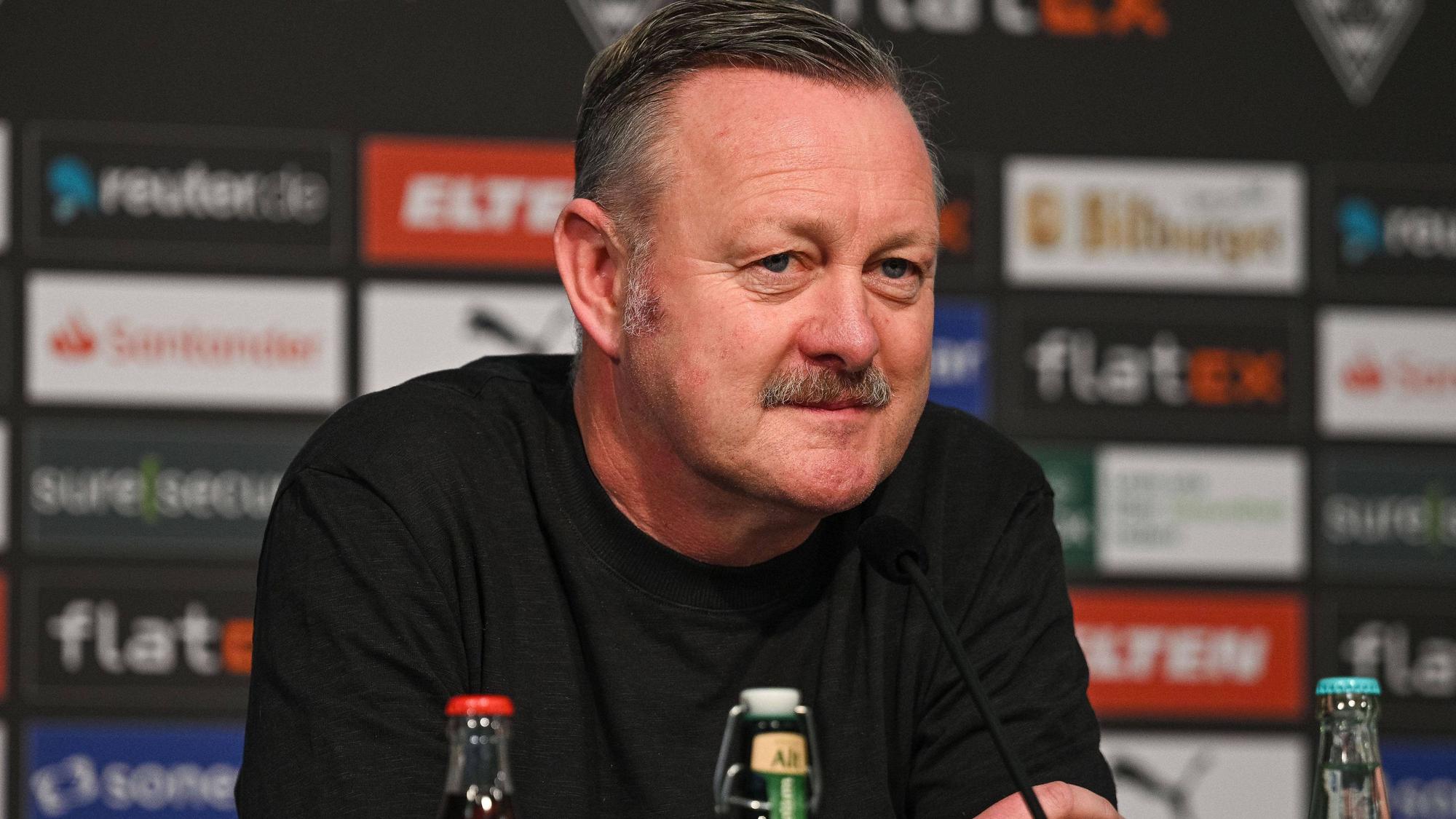 Roland Virkus, Manager von Borussia Mönchengladbach, bei einer Pressekonferenz am 20. Januar 2023 im Borussia-Park. Er schaut verschmitzt und ernst und trägt einen schwarzen Pullover.