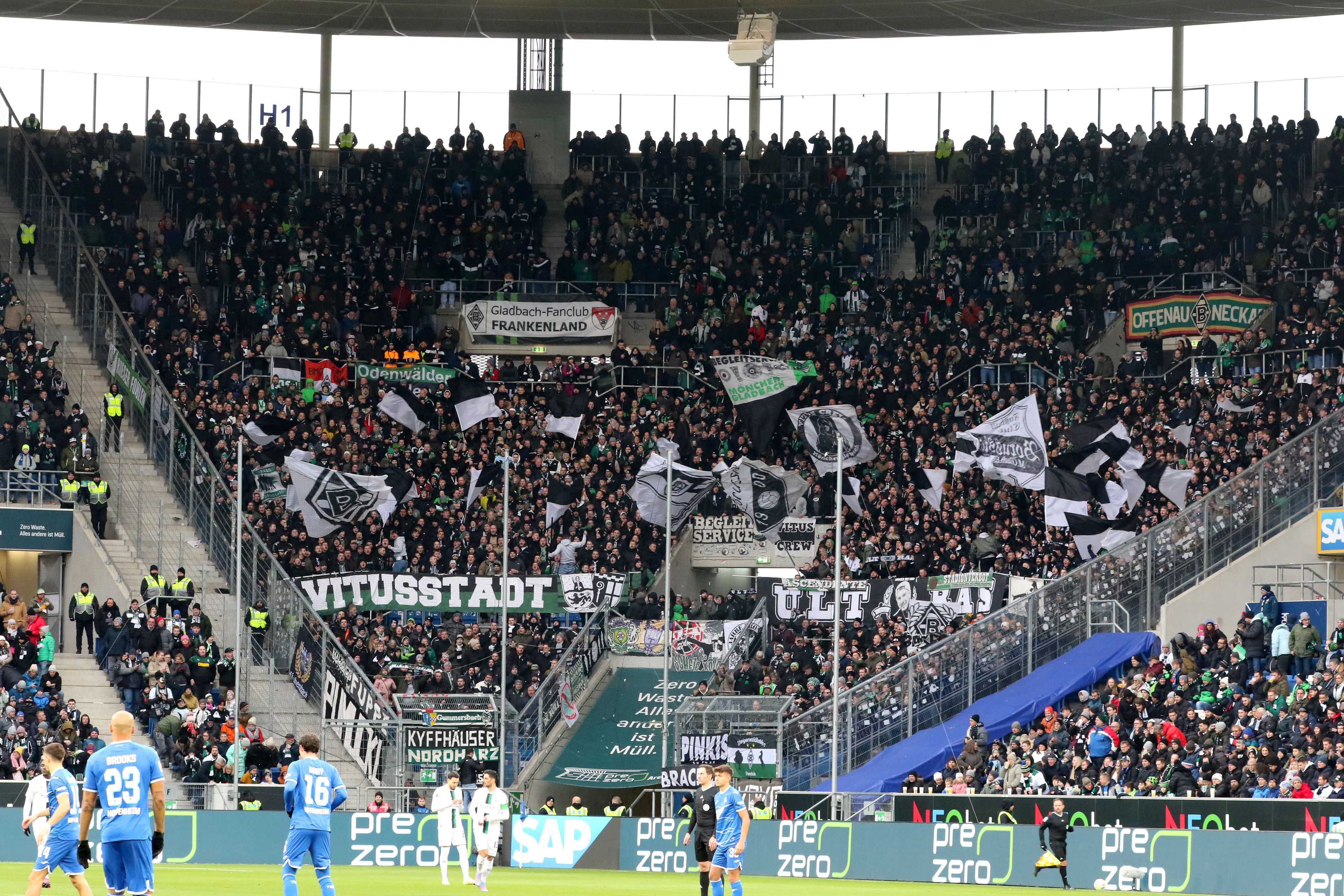 Der Fan-Block von Borussia Mönchengladbach während des Bundesliga-Spiels (28. Januar 2023) bei der TSG Hoffenheim in der Sinsheimer Arena. Zu sehen sind Banner der Gladbach-Ultras und Fahnen.