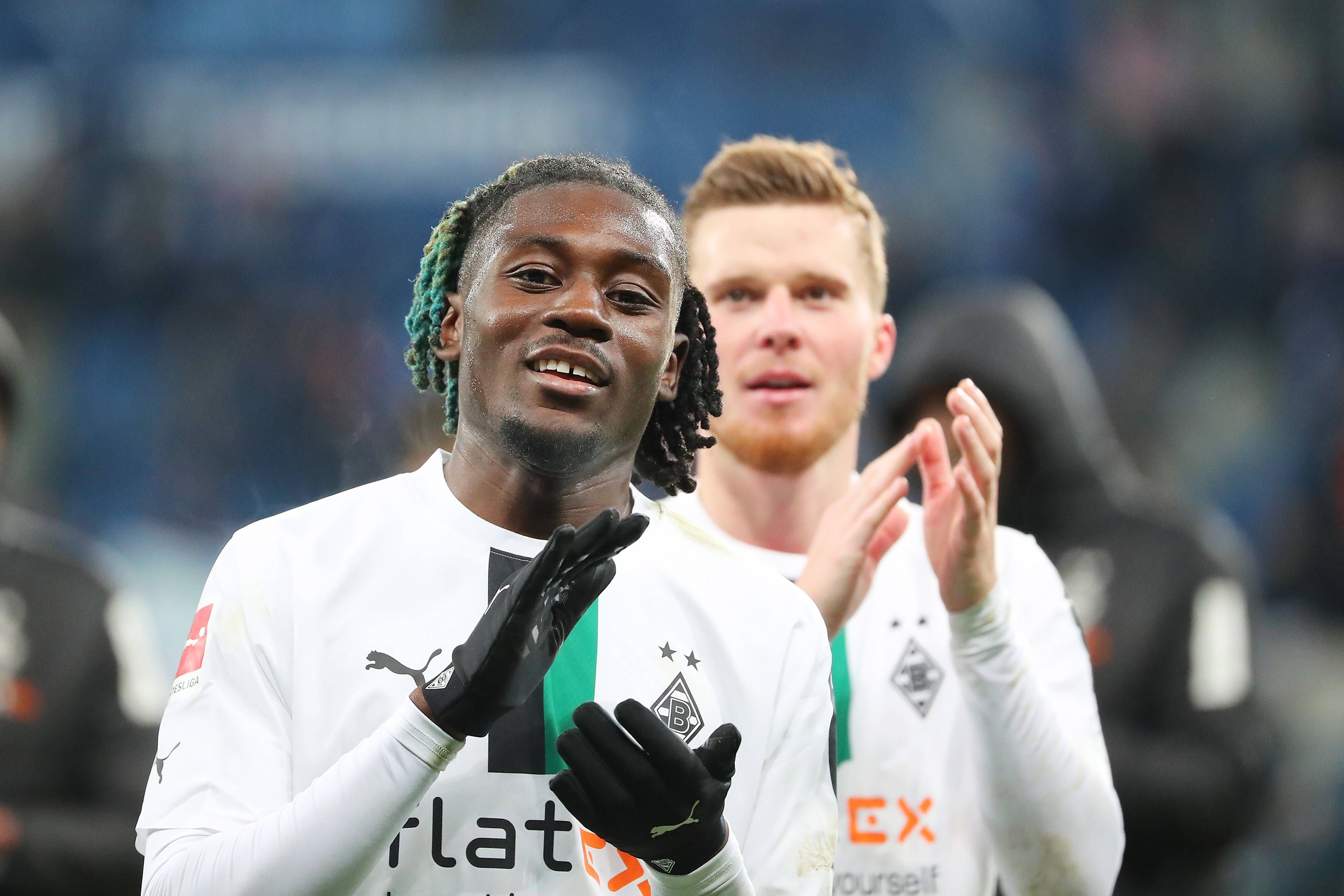 Gute Laune bei Manu Koné von Borussia Mönchengladbach. Der Franzose feierte am Samstag (28. Januar 2023) mit seinem Team einen 4:1-Sieg bei der TSG 1899 Hoffenheim. Das Foto zeigt ihn im weißen langärmligen Trikot und schwarzen Handschuhen in die Hände klatschend.