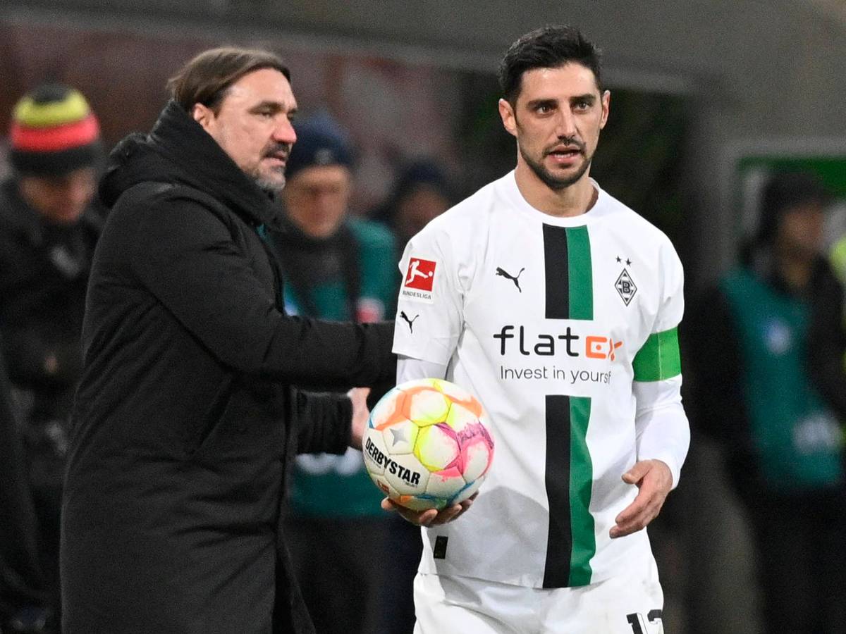 Daniel Farke (l.), Trainer von Borussia Mönchengladbach, gibt Kapitän Lars Stindl im Bundesliga-Spiel am 28. Januar 2023 bei der TSG Hoffenheim den Ball und spricht mit dem Gladbach-Spieler, der das weiße Heimtrikot von Borussia trägt.