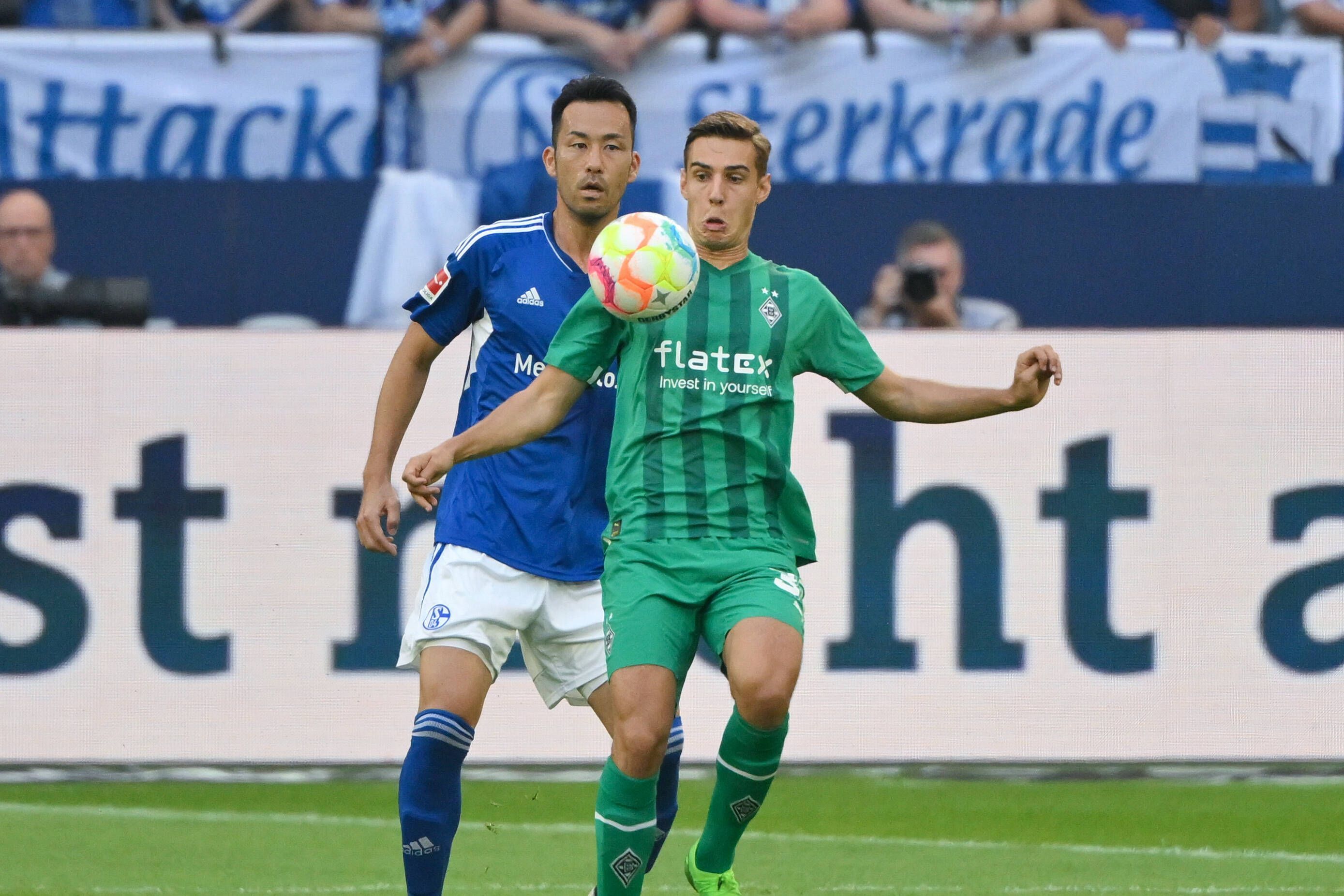 Florian Neuhaus (r.) von Borussia Mönchengladbach steht beim Bundesliga-Auswärtsspiel bei Schalke 04 am 13. August 2022 vor Maya Yoshida und blickt fokussiert auf den Ball vor ihm.