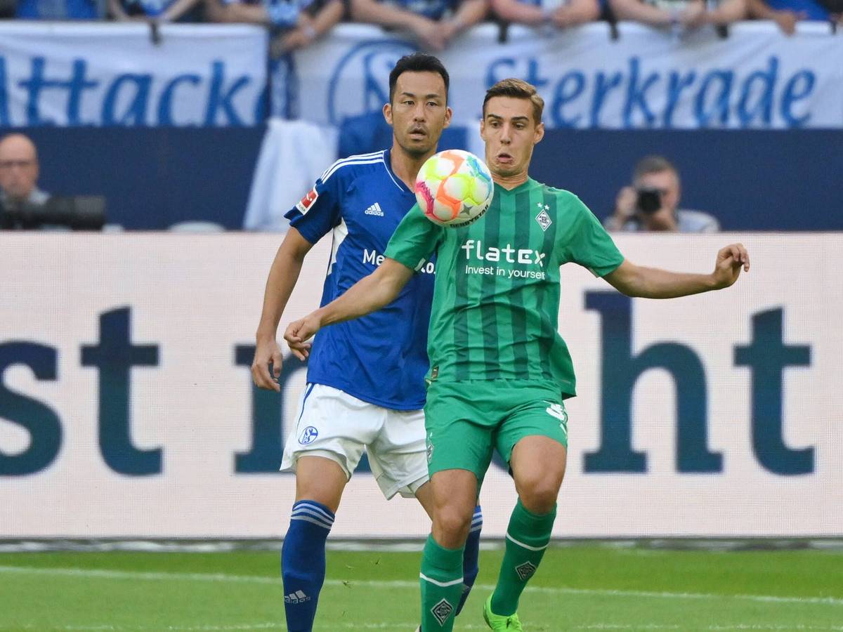 Florian Neuhaus (r.) von Borussia Mönchengladbach steht beim Bundesliga-Auswärtsspiel bei Schalke 04 am 13. August 2022 vor Maya Yoshida und blickt fokussiert auf den Ball vor ihm.
