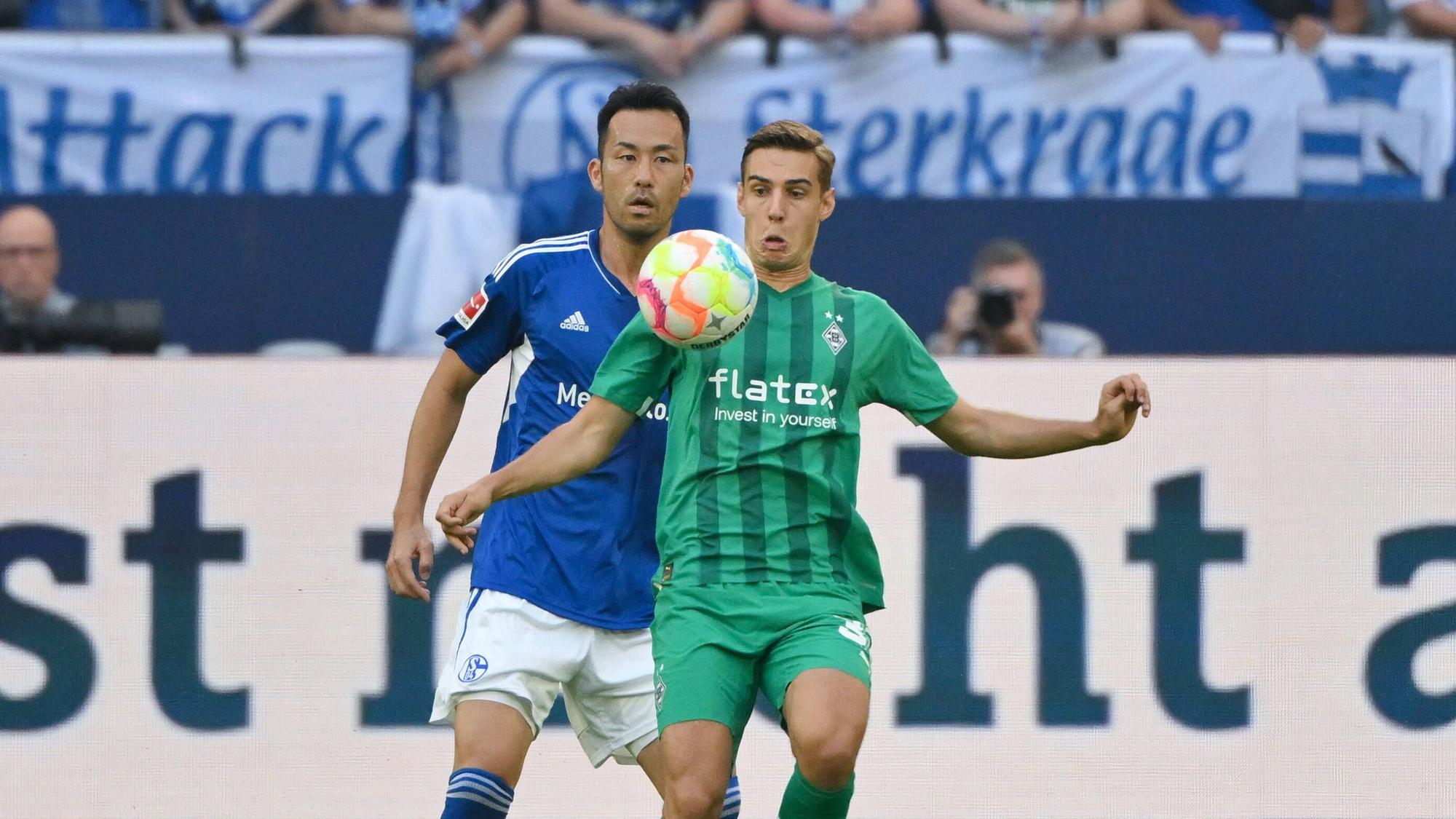 Florian Neuhaus (r.) von Borussia Mönchengladbach steht beim Bundesliga-Auswärtsspiel bei Schalke 04 am 13. August 2022 vor Maya Yoshida und blickt fokussiert auf den Ball vor ihm.