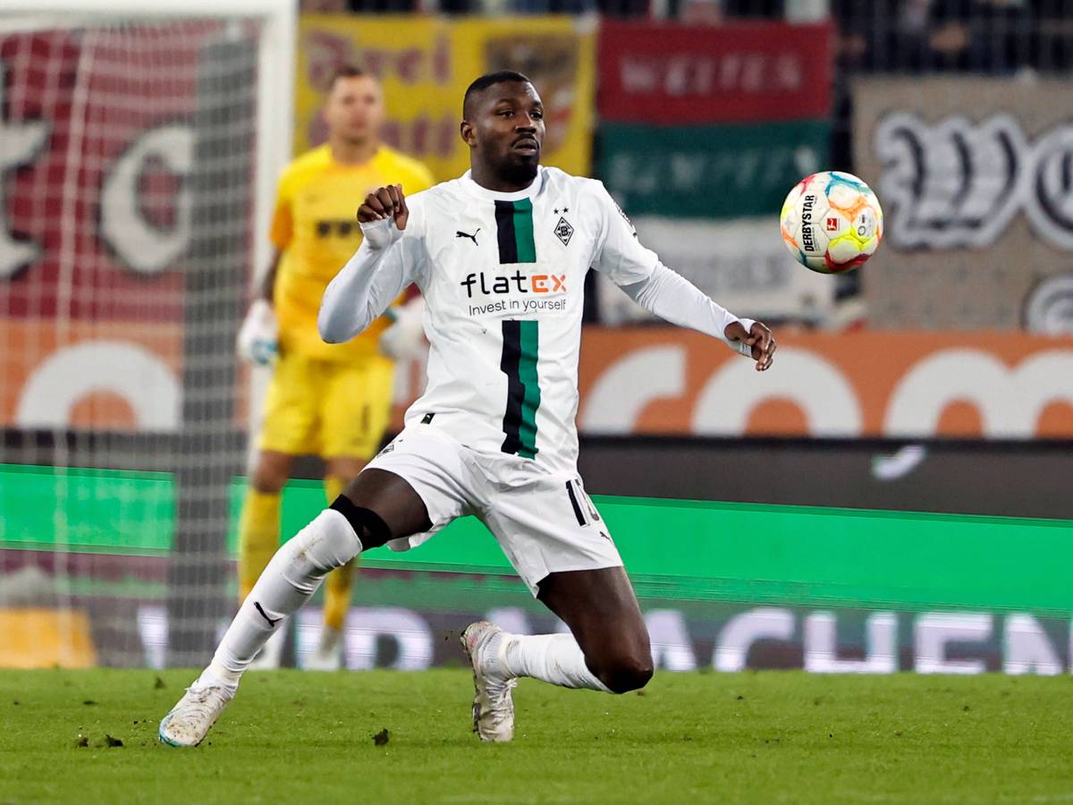 Marcus Thuram schaut im Bundesliga-Spiel von Borussia Mönchengladbach beim FC Augsburg am 25. Januar 2023 fokussiert auf den fliegenden Ball. Thuram trägt das weiße Gladbach-Heimtrikot.