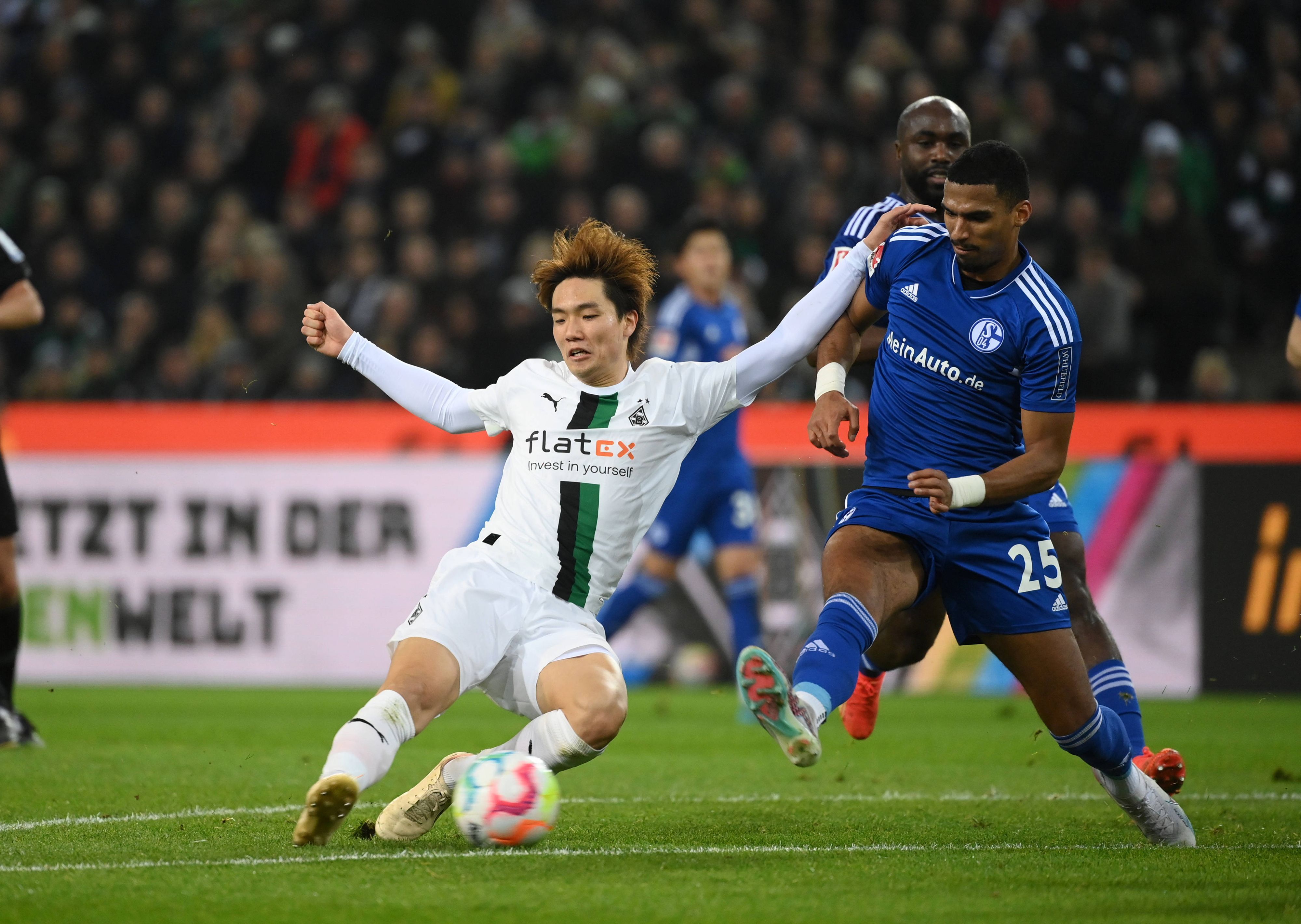 Ko Itakura (l.) von Borussia Mönchengladbach grätscht am 4. Februar 2023 in den Ball und will sich im Duell mit Moritz Jenz von Schalke 04 durchsetzen.