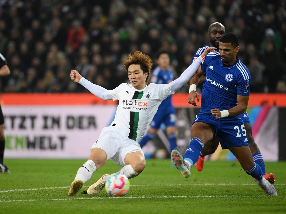 Ko Itakura (l.) von Borussia Mönchengladbach grätscht am 4. Februar 2023 in den Ball und will sich im Duell mit Moritz Jenz von Schalke 04 durchsetzen.