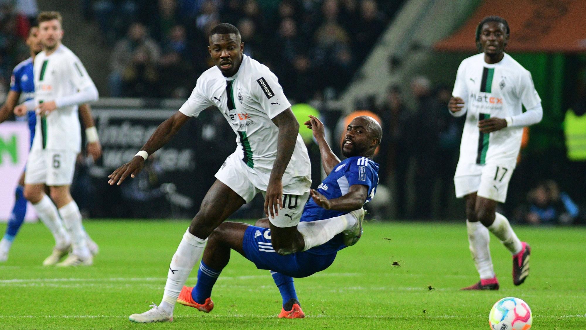 Gladbach-Stürmer Marcus Thuram (M.) im Zweikampf mit Eder Balanta von Schalke 04 während des Bundesliga-Duells am 4. Februar 2023 im Borussia-Park. Im Hintergrund schauen Koné und Kramer zu.