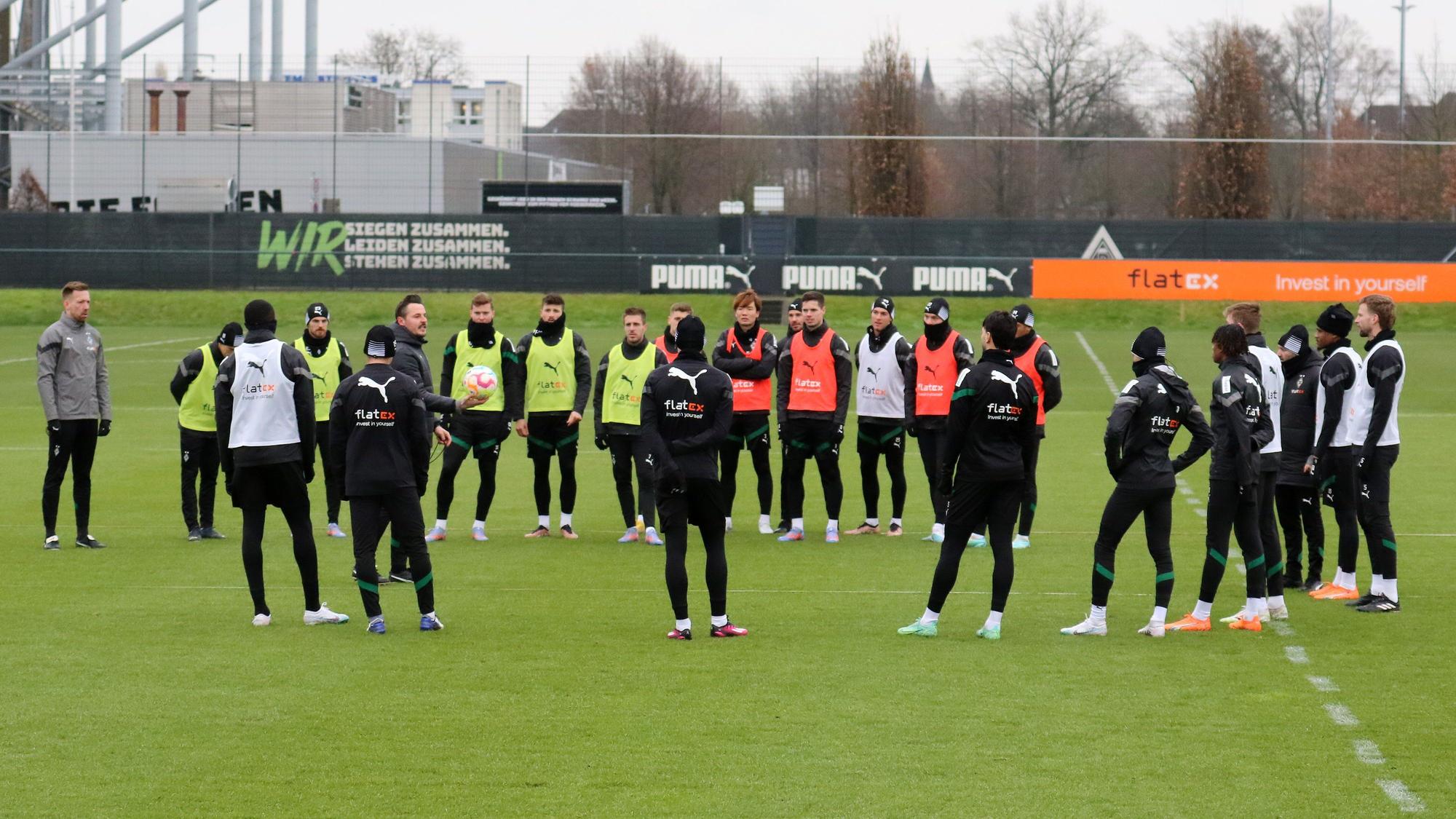 Das Team von Borussia Mönchengladbach steht bei einer Trainingseinheit am 2. Februar 2023 im Borussia-Park im Kreis zusammen. Co-Trainer Edmund Riemer gibt Anweisungen, einige Spieler tragen bunte Leibchen.