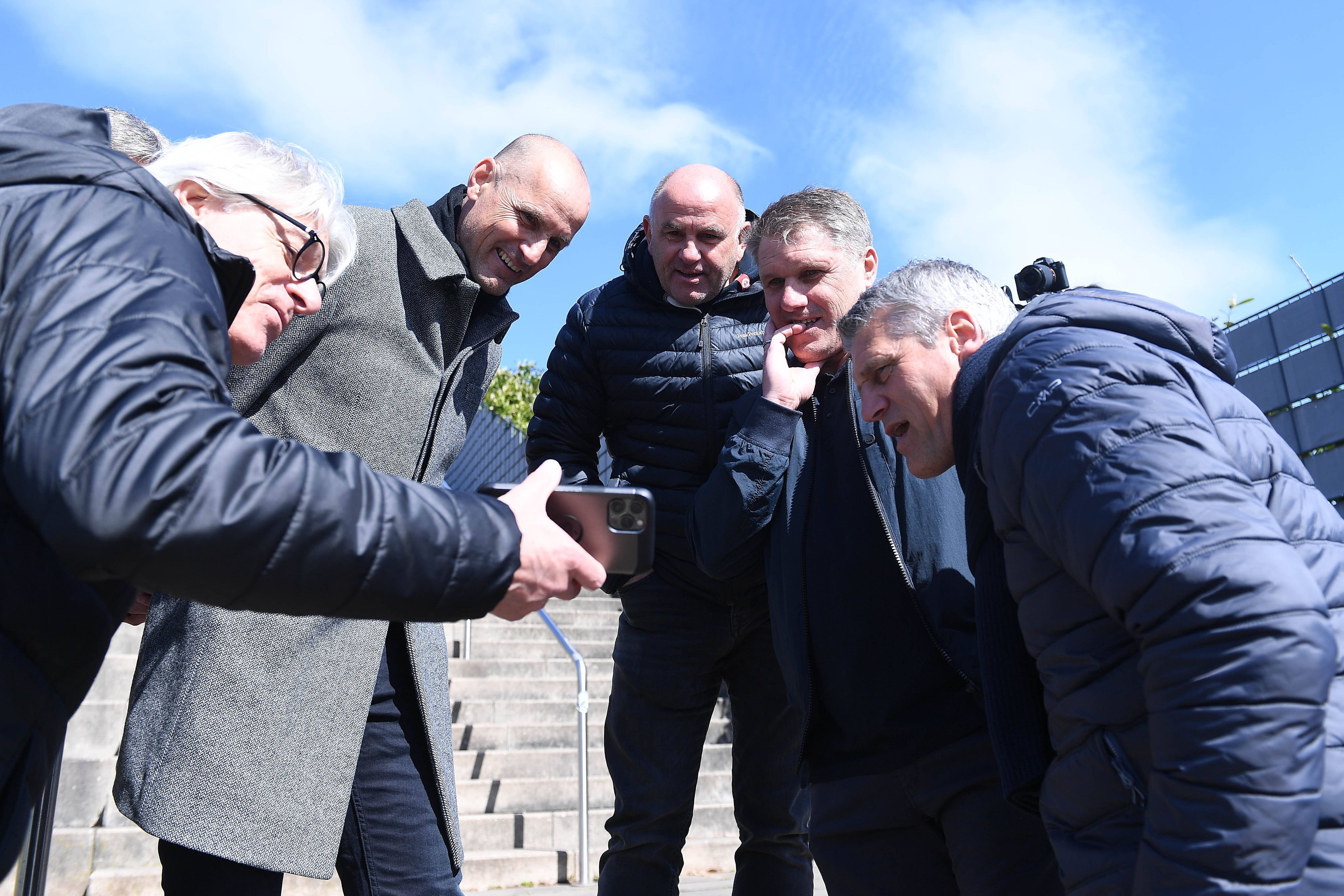 Elmar Kreuels (l.) besucht am 3. April 2022 mit den Gladbach-Pokalsiegern von 1995 das Gelände, wo einst das Bökelberg-Stadion in Mönchengladbach gestanden hat. Zu sehen sind, rechts neben Kreuels, Heiko Herrlich, Christian Hochstätter, Michael Klinkert und Joachim Stadler. Kreuels zeigt ihnen auf seinem Smartphone Bilder und Videos.