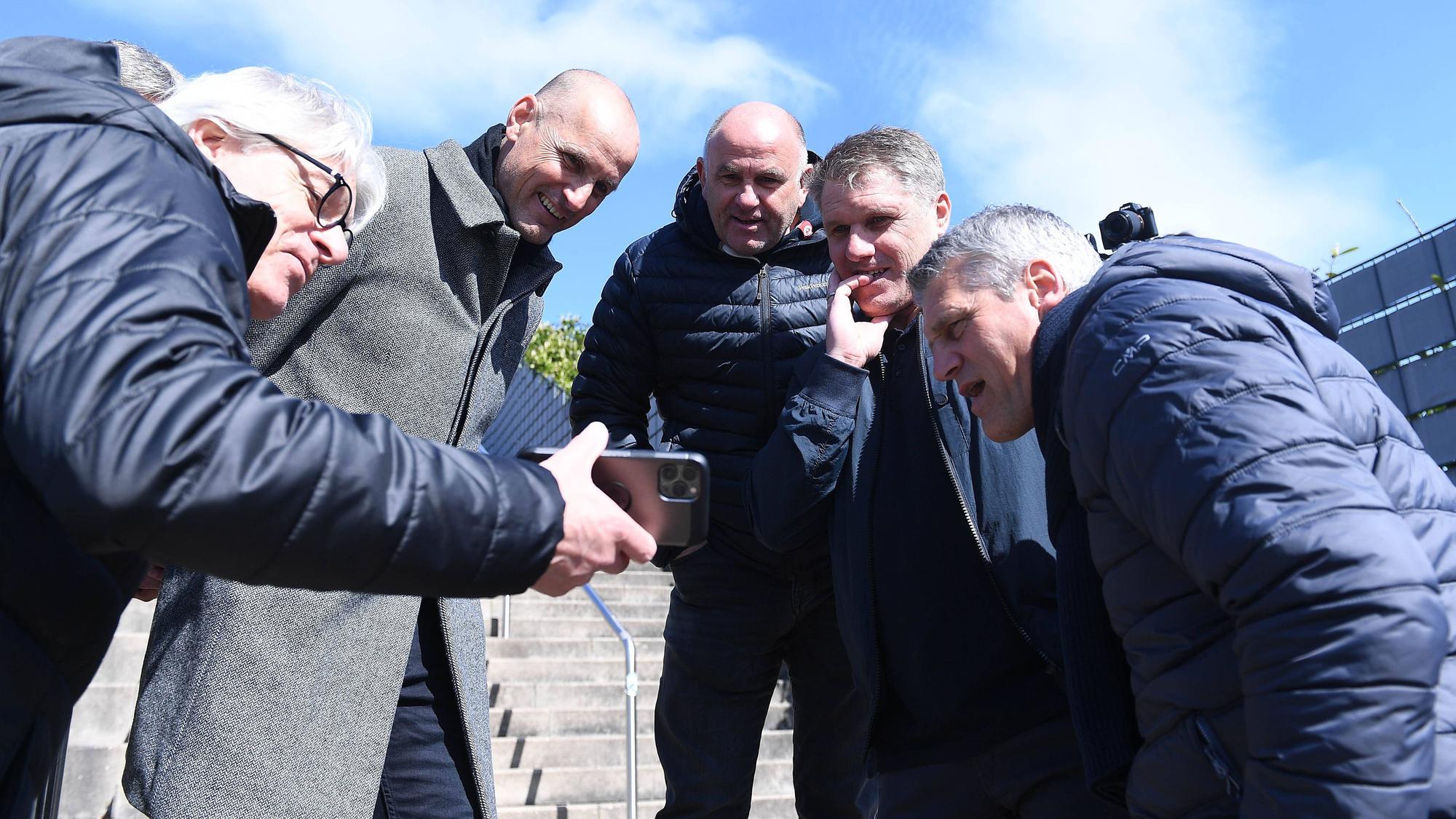 Elmar Kreuels (l.) besucht am 3. April 2022 mit den Gladbach-Pokalsiegern von 1995 das Gelände, wo einst das Bökelberg-Stadion in Mönchengladbach gestanden hat. Zu sehen sind, rechts neben Kreuels, Heiko Herrlich, Christian Hochstätter, Michael Klinkert und Joachim Stadler. Kreuels zeigt ihnen auf seinem Smartphone Bilder und Videos.