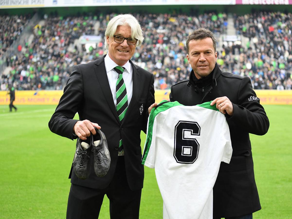 Der Mann für die Traditionspflege im Borussia-Park und der Weltmeister: Elmar Kreuels (l.) bekommt von Ex-Gladbach-Star Lothar Matthäus (r.) am 22. April 2017 dessen Original-Trikot aus alten Fohlen-Tagen samt Fußballschuhe überreicht. Beide lächeln in die Kamera. Matthäus zeigt sein Gladbach-Jersey, Kreuels hält die Schuhe in seiner rechten Hand.