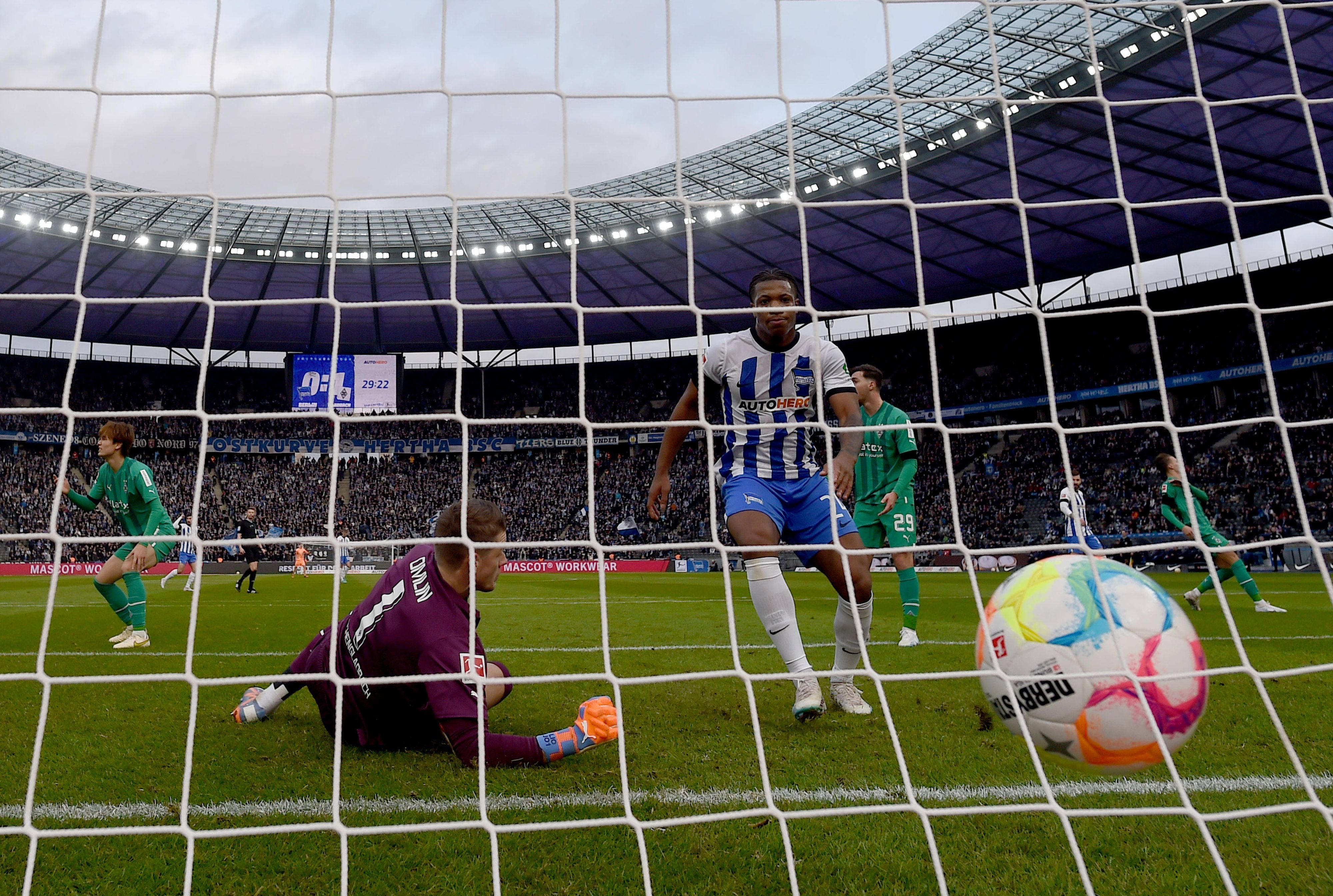 Jessic Ngankam (r.)  schiebt den Ball zum zwischenzeitlichen 1:1-Ausgleich im Bundesliga-Spiel von Hertha BSC gegen Borussia Mönchengladbach ein. Jonas Omlin kann den Gegentreffer nicht mehr verhindern. Zu sehen ist, wie der Ball ins Netz des Borussia-Tores fliegt. Omlin springt vergeblich hinterher.