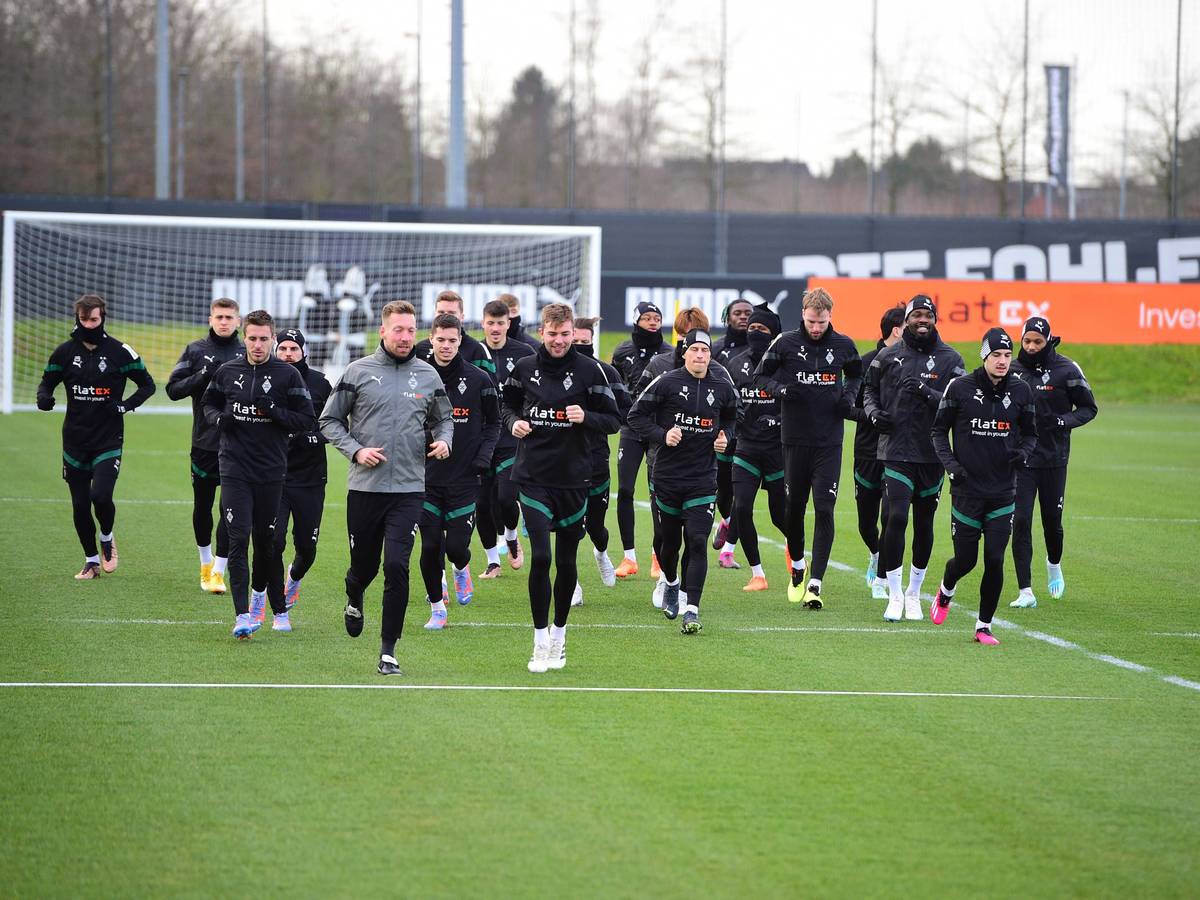 Die Spieler von Borussia Mönchengladbach laufen am 1. Februar 2023 gemeinschaftlich eine Runde auf dem Trainingsplatz-Rasen im Borussia-Park. Die Spieler tragen schwarze Gladbach-Trainingskleidung.