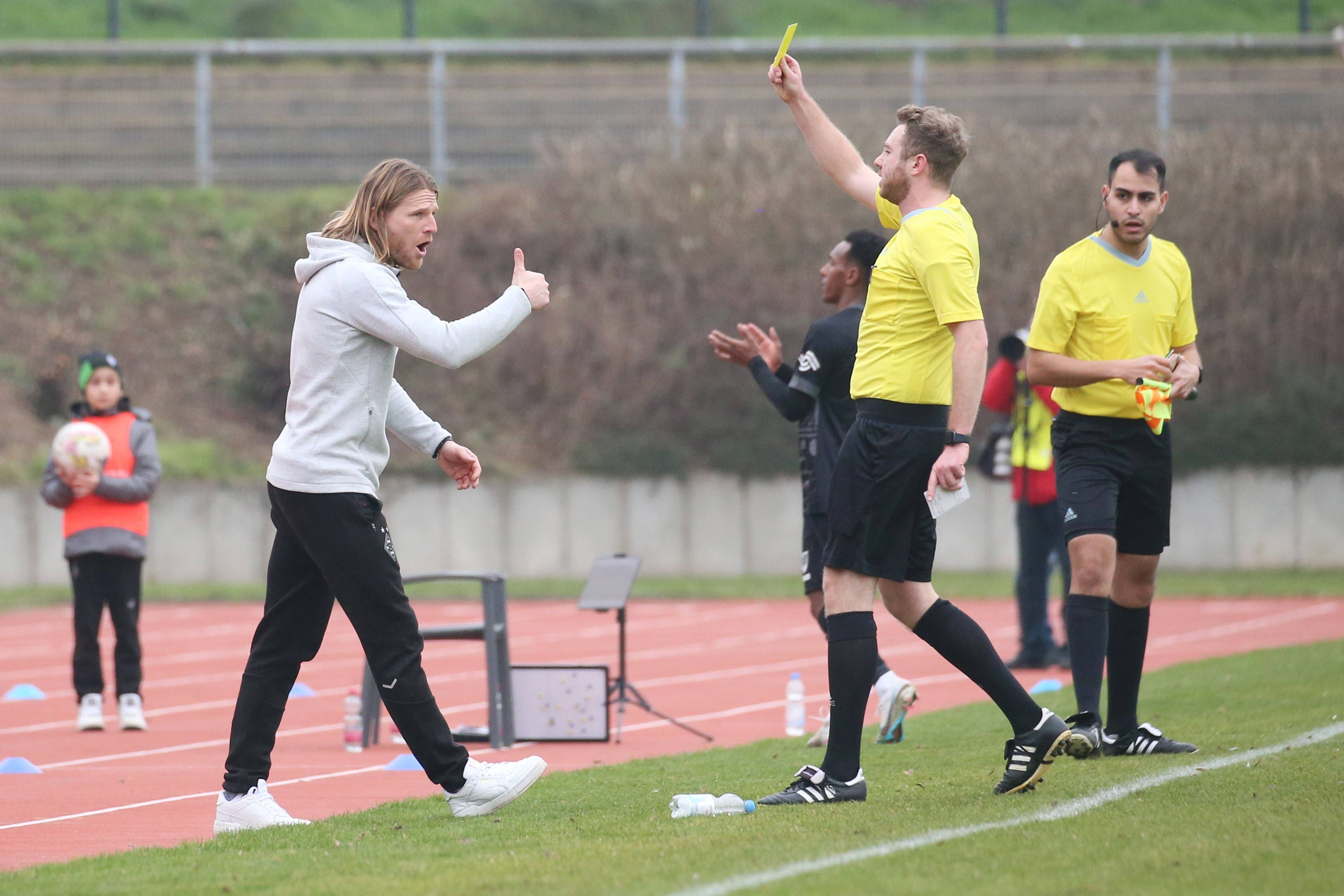 Eugen Polanski (l.) sieht beim Spiel der U23 von Borussia Mönchengladbach gegen Preußen Münster am 12. Februar 2023 die Gelbe Karte vom Schiedsrichter. Aufgenommen wurde das Foto, als Polanski die Verwarnung im Grenzlandstadion gezeigt bekommt. Polanski streckt den Daumen als Reaktion nach oben.