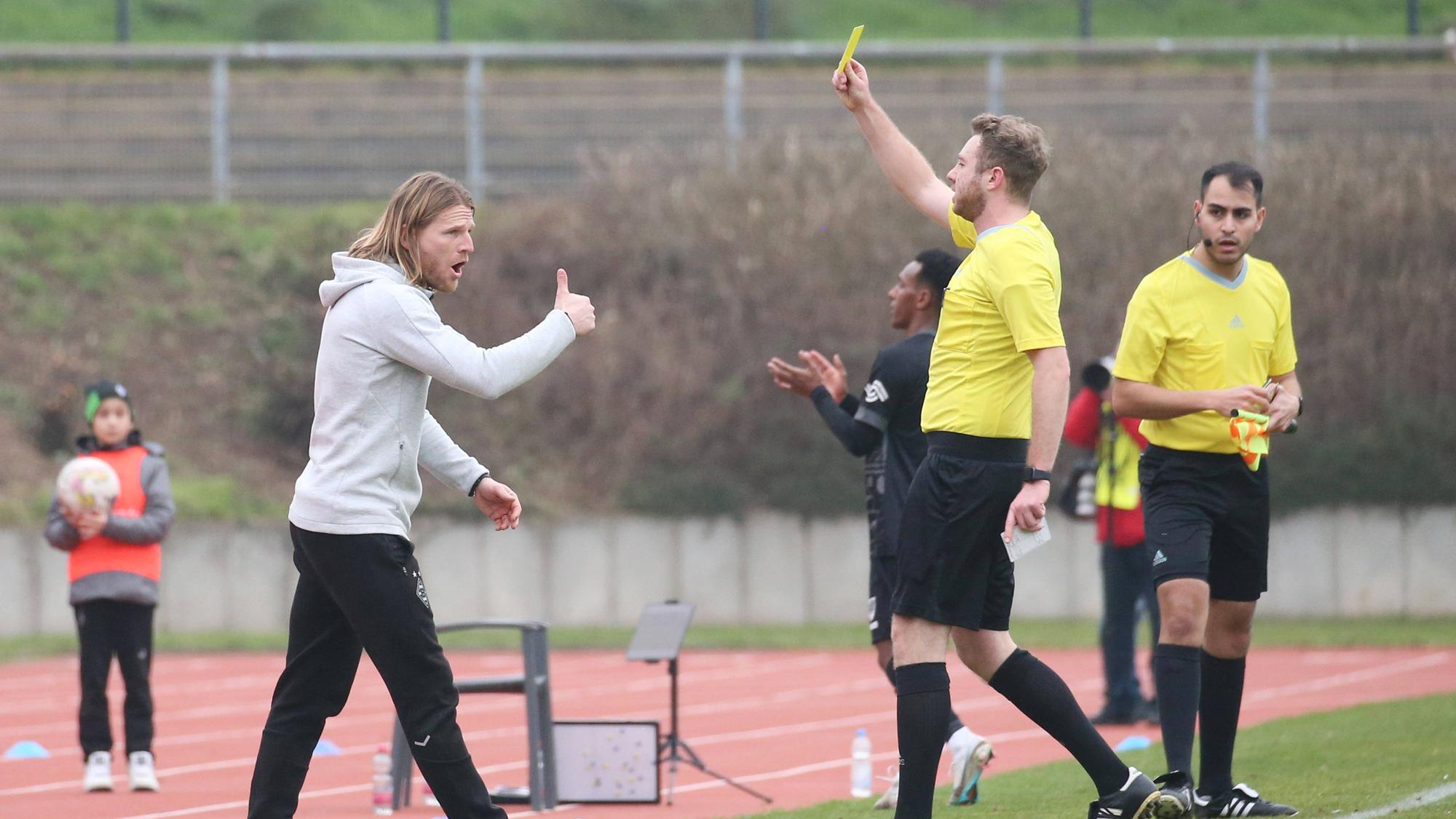 Eugen Polanski (l.) sieht beim Spiel der U23 von Borussia Mönchengladbach gegen Preußen Münster am 12. Februar 2023 die Gelbe Karte vom Schiedsrichter. Aufgenommen wurde das Foto, als Polanski die Verwarnung im Grenzlandstadion gezeigt bekommt. Polanski streckt den Daumen als Reaktion nach oben.