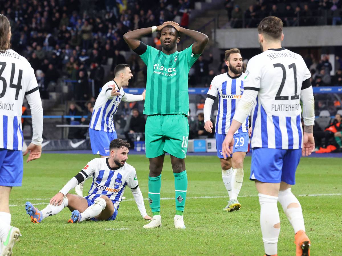 Marcus Thuram (in grün) von Borussia Mönchengladbach fasst sich nach einer vergebenen Torchance im Bundesliga-Spiel bei Hertha BSC mit den Händen an den Kopf. Bei dem Foto vom 12. Februar 2023 stehen fünf Spieler von Hertha BSC um den Gladbach-Stürmer herum.