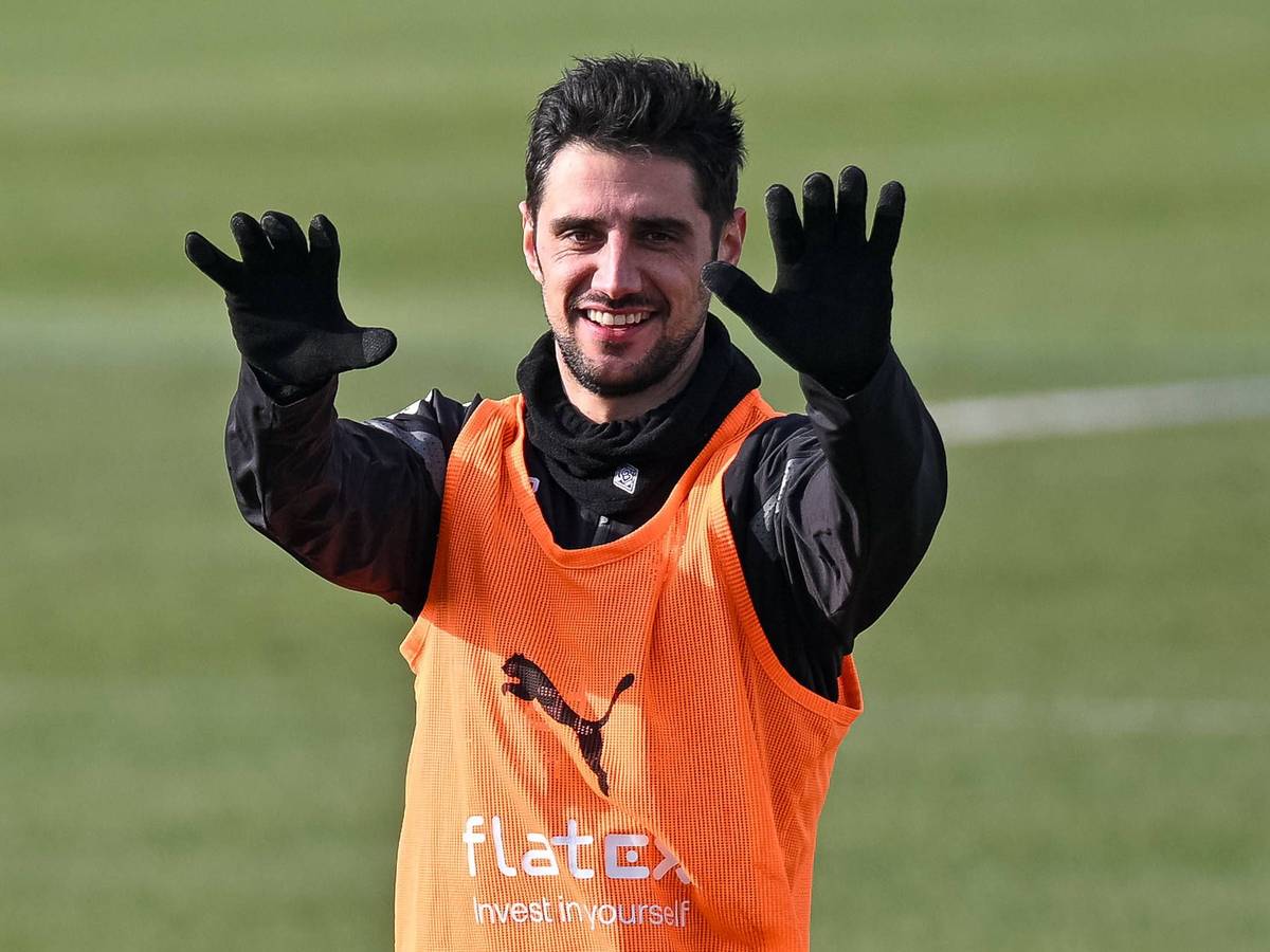 Lars Stindl streckt im Training von Borussia Mönchengladbach beide Arme nach vorne und lächelt. Der Gladbach-Kapitän trägt bei der Einheit auf dem Trainingsplatz im Borussia-Park am 9. Februar 2023 dunkle Trainingskleidung und ein Leibchen.