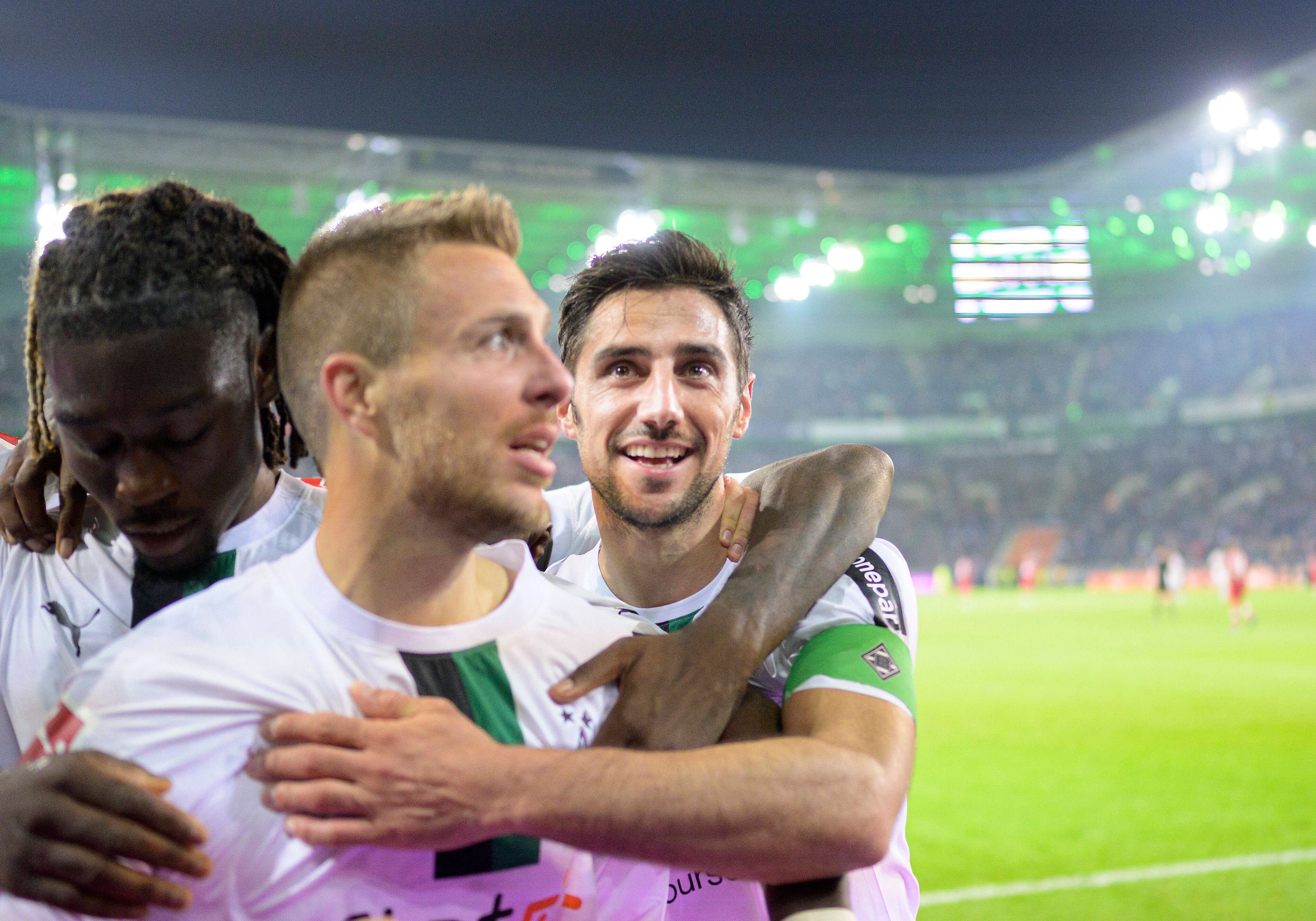 Patrick Herrmann (M.) von Borussia Mönchengladbach jubelt gemeinsam mit Manu Kone (l.) und Lars Stindl nach Herrmanns Tor im Bundesliga-Spiel gegen den VfB Stuttgart am 4. November 2022. Koné und Stindl legen ihre Arme um den Torschützen, der vor der Nordkurve feiert.