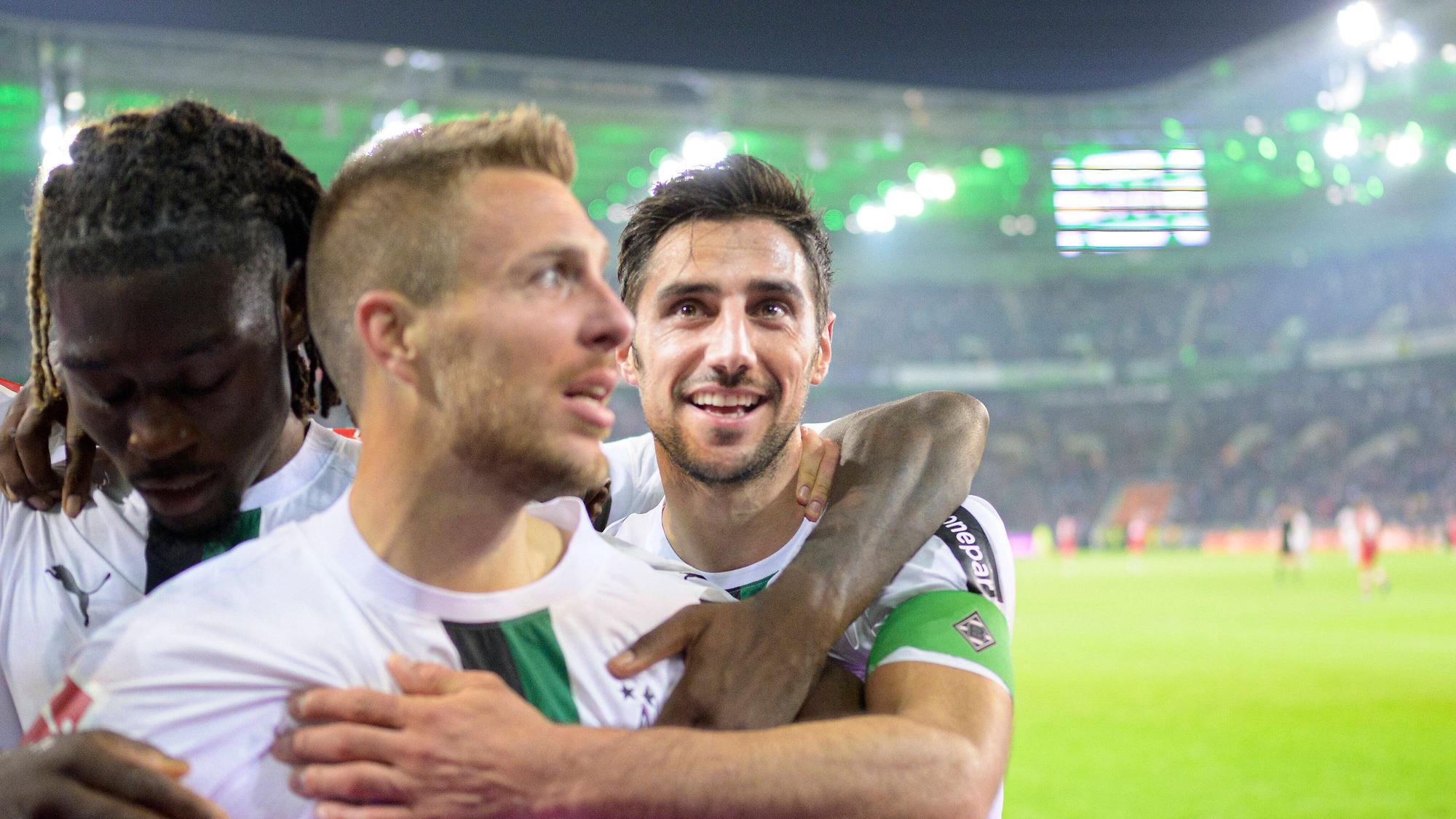 Patrick Herrmann (M.) von Borussia Mönchengladbach jubelt gemeinsam mit Manu Kone (l.) und Lars Stindl nach Herrmanns Tor im Bundesliga-Spiel gegen den VfB Stuttgart am 4. November 2022. Koné und Stindl legen ihre Arme um den Torschützen, der vor der Nordkurve feiert.