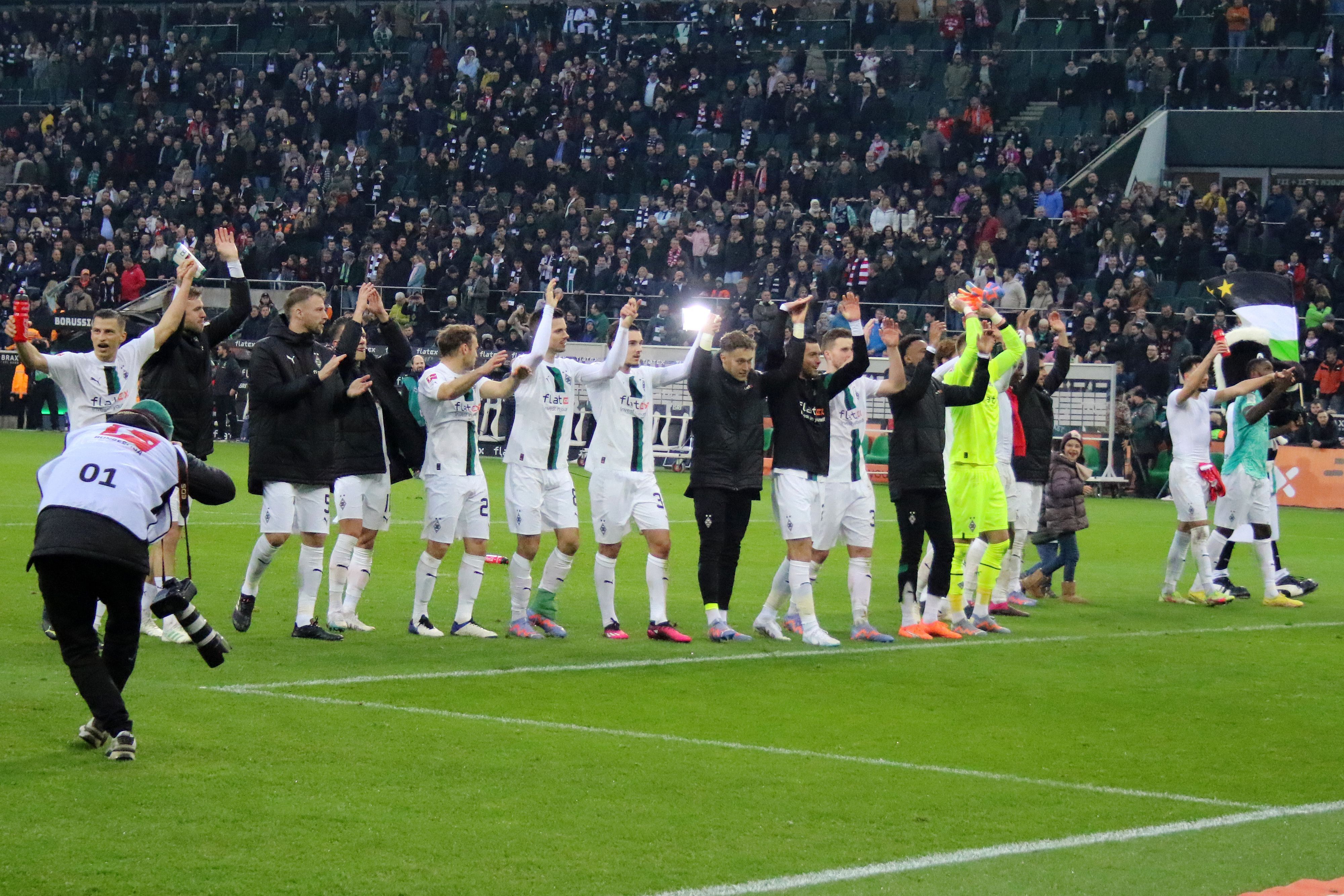 Die Mannschaft von Borussia Mönchengladbach feiert nach dem 3:2-Heimsieg gegen den FC Bayern München am 18. Februar 2023 mit den Fans im Borussia-Park. Die Spieler halten sich an den Händen und machen die La-Ola-Welle vor der Nordkurve.