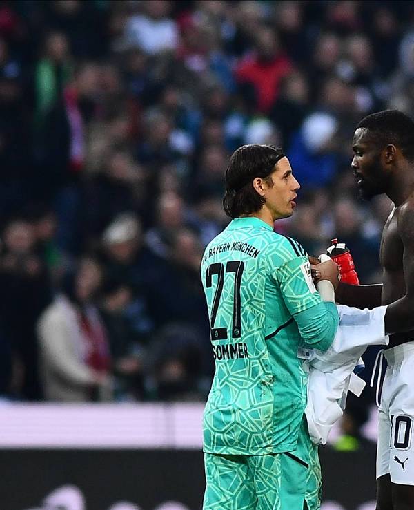 Ex-Gladbach-Torwart Yann Sommer (l.) klatscht sich nach der Bundesliga-Niederlage seines neuen Klubs Bayern München mit Borussia-Stürmer Marcus Thuram (r.) ab. Thuram hat einen nackten Oberkörper und möchte das Trikot mit Sommer tauschen.