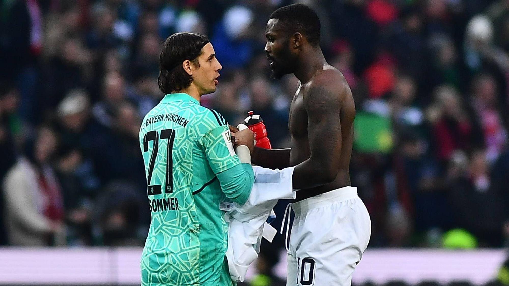 Ex-Gladbach-Torwart Yann Sommer (l.) klatscht sich nach der Bundesliga-Niederlage seines neuen Klubs Bayern München mit Borussia-Stürmer Marcus Thuram (r.) ab. Thuram hat einen nackten Oberkörper und möchte das Trikot mit Sommer tauschen.