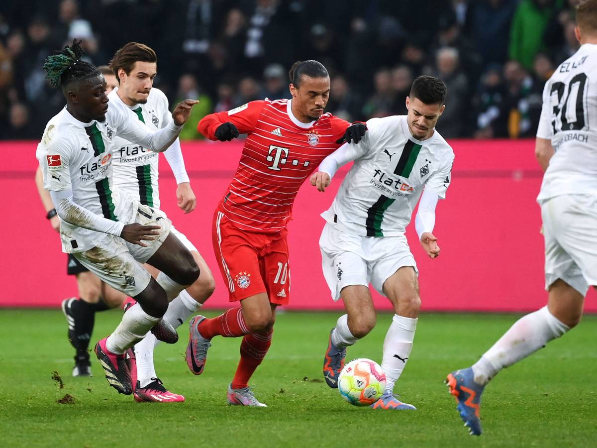 Julian Weigl (r.) bestreitet kurz vor seiner verletzungsbedingten Auswechslung im Spiel von Borussia Mönchengladbach gegen den FC Bayern München am 18. Februar 2023 einen Zweikampf mit Leroy Sané. Teamkollegen Manu Koné und Florian Neuhaus (v.l.n.r.) unterstützen ihn und greifen den Bayern-Spieler von der anderen Seite an.