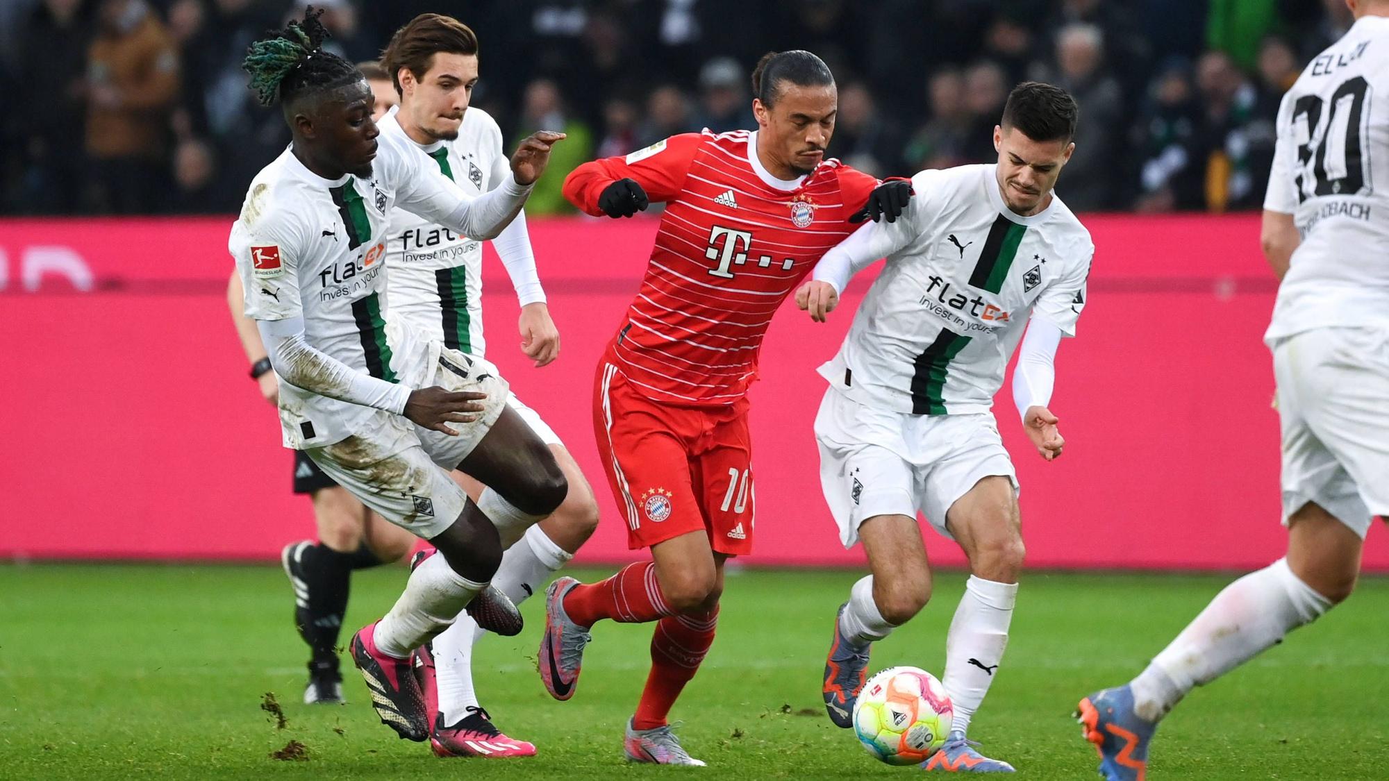 Julian Weigl (r.) bestreitet kurz vor seiner verletzungsbedingten Auswechslung im Spiel von Borussia Mönchengladbach gegen den FC Bayern München am 18. Februar 2023 einen Zweikampf mit Leroy Sané. Teamkollegen Manu Koné und Florian Neuhaus (v.l.n.r.) unterstützen ihn und greifen den Bayern-Spieler von der anderen Seite an.