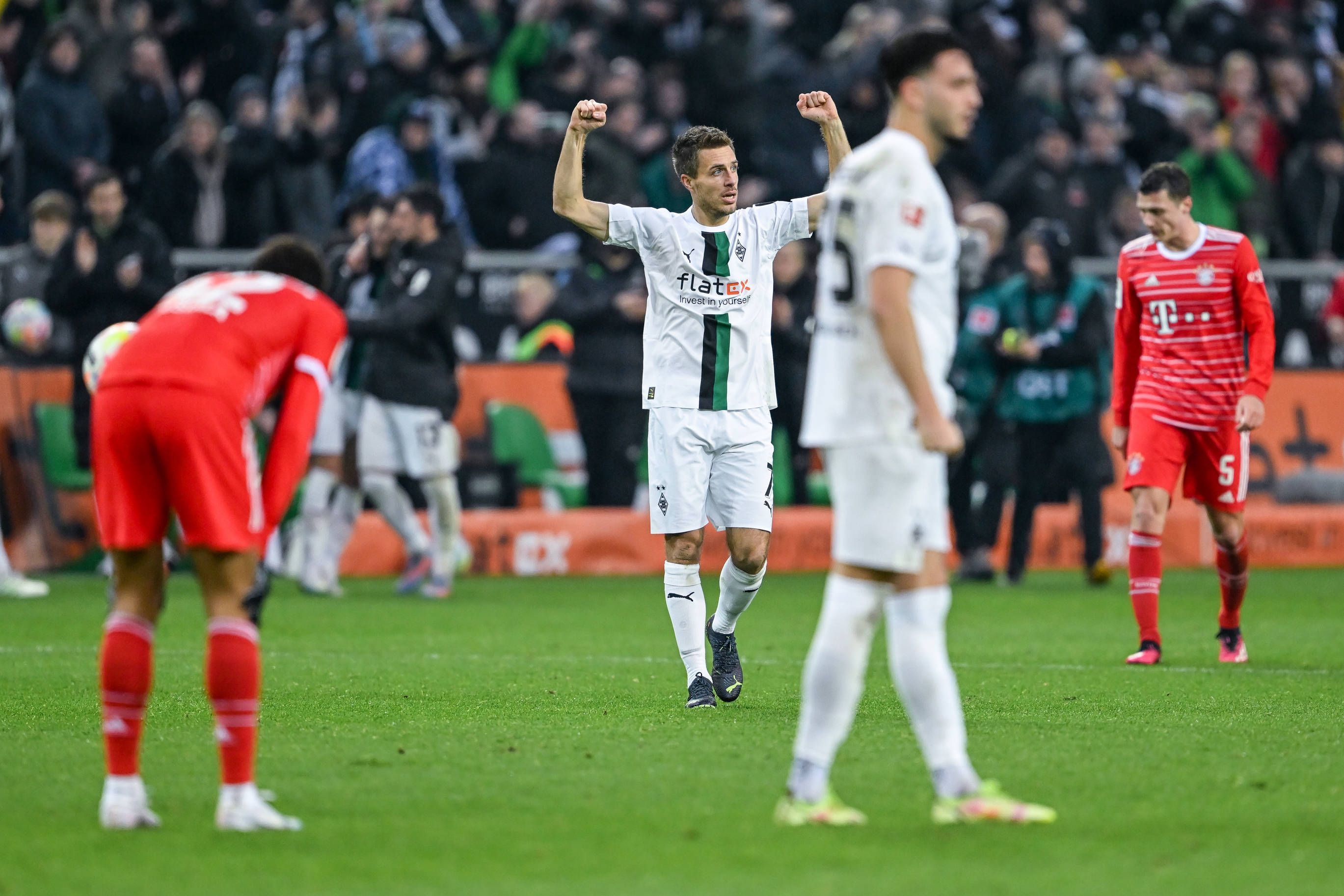 Patrick Herrmann reißt nach dem Schlusspfiff des Bundesliga-Spiels von Borussia Mönchengladbach gegen den FC Bayern München am 18. Februar 2023 die Arme nach oben. In der Nähe von Herrmann stehen die Bayern-Profis und Teamkollege Ramy Bensebaini. Herrmann trägt das weiße Gladbach-Heimtrikot.