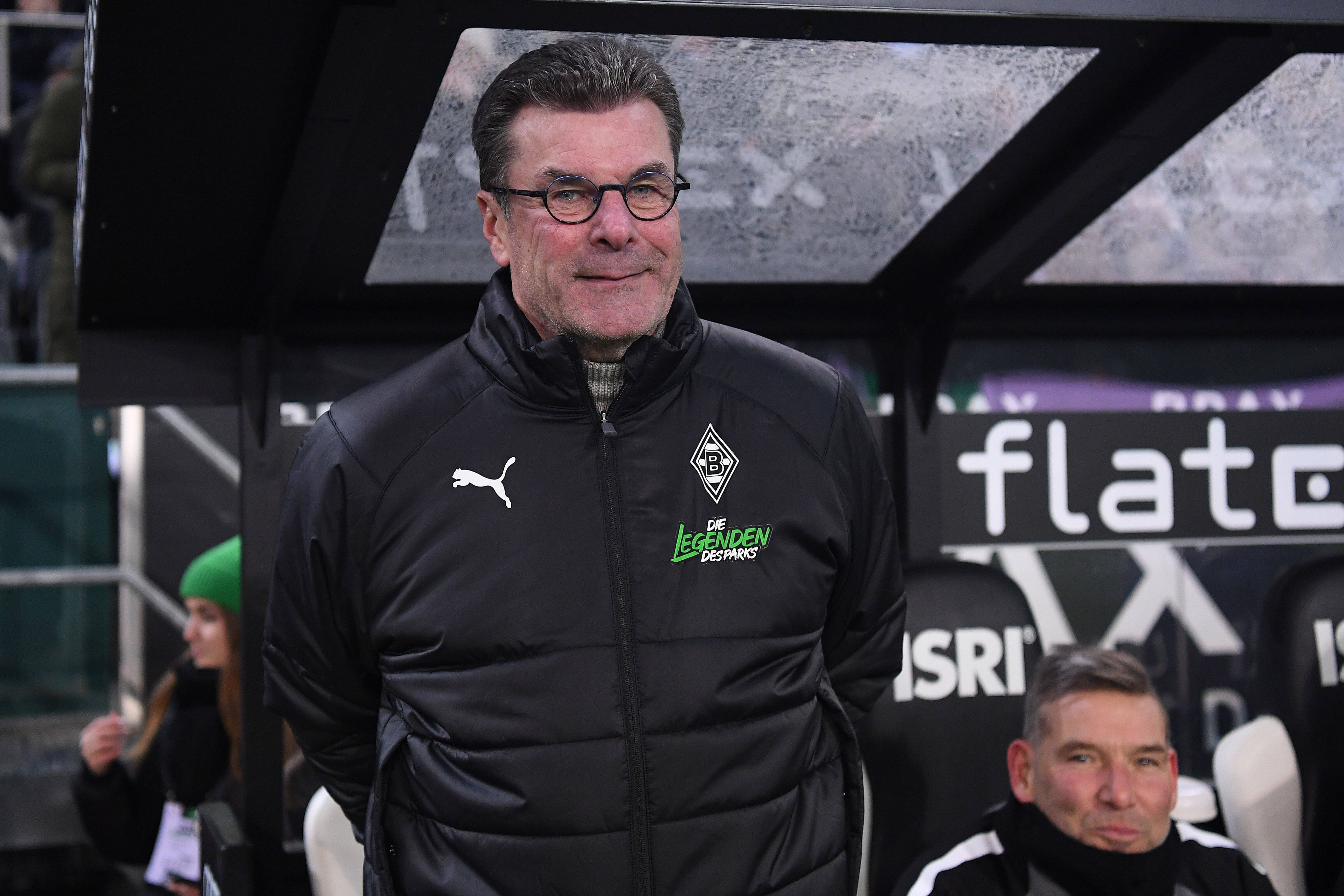 Ex-Gladbach-Coach Dieter Hecking kehrt auf die Trainerbank zurück. Der 58-Jährige, hier zu sehen an der Seitenlinie während des Legendenspiels (17. Dezember 2022) im Borussia-Park, übernimmt bei Zweitligist 1. FC Nürnberg das Amt bis zum Saisonende. Hecking trägt eine Brille, er lächelt.