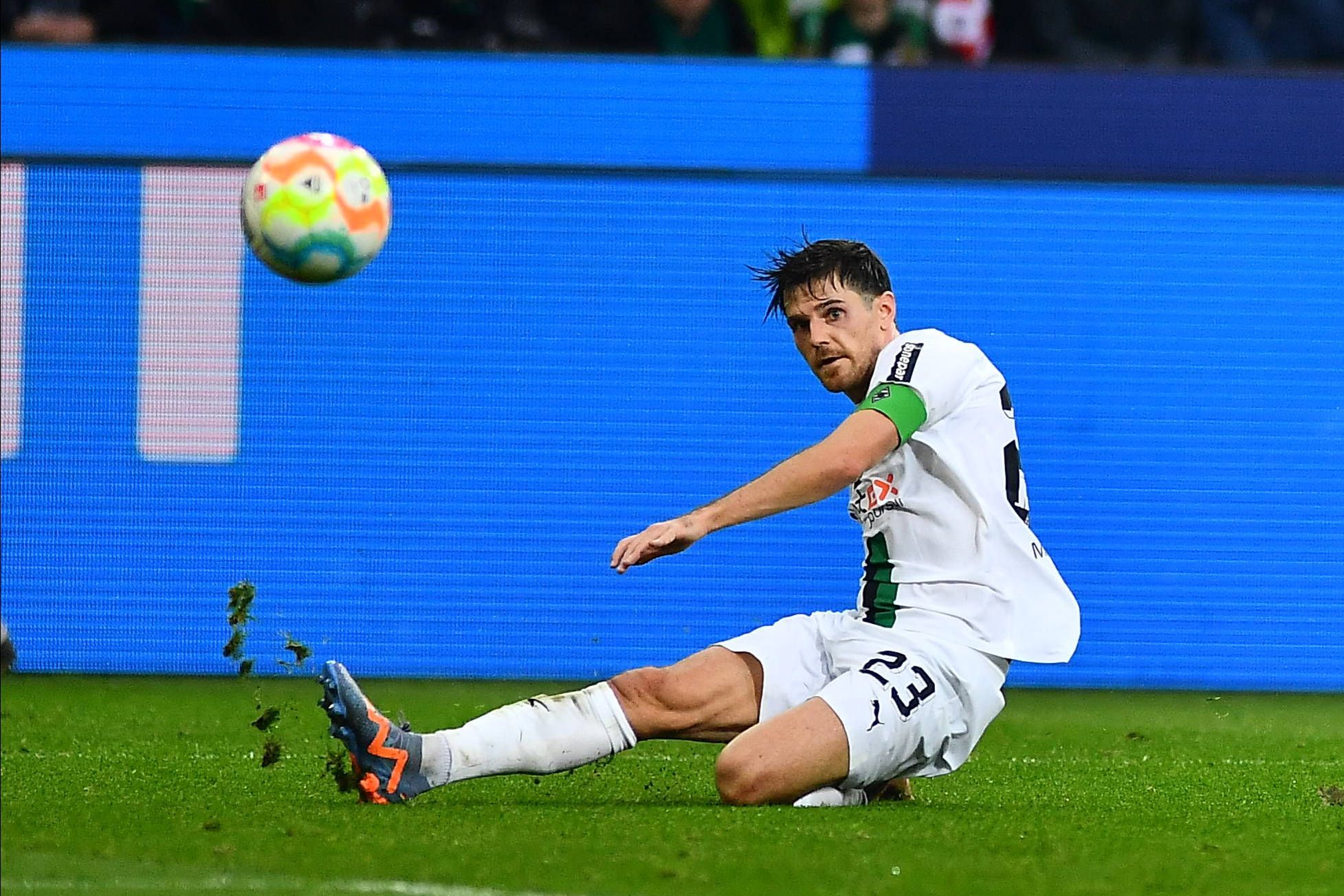 Jonas Hofmann trägt im Bundesliga-Spiel von Borussia Mönchengladbach gegen den FC Bayern München am 18. Februar 2023 die Gladbach-Kapitänsbinde. Der Borussia-Spieler grätscht auf dem Rasen im Borussia-Park und blickt auf den fliegenden Ball.