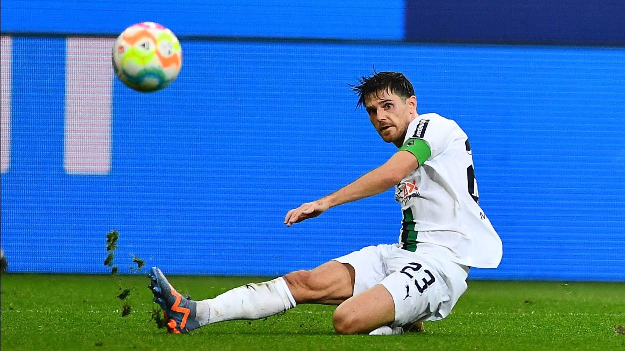 Jonas Hofmann trägt im Bundesliga-Spiel von Borussia Mönchengladbach gegen den FC Bayern München am 18. Februar 2023 die Gladbach-Kapitänsbinde. Der Borussia-Spieler grätscht auf dem Rasen im Borussia-Park und blickt auf den fliegenden Ball.